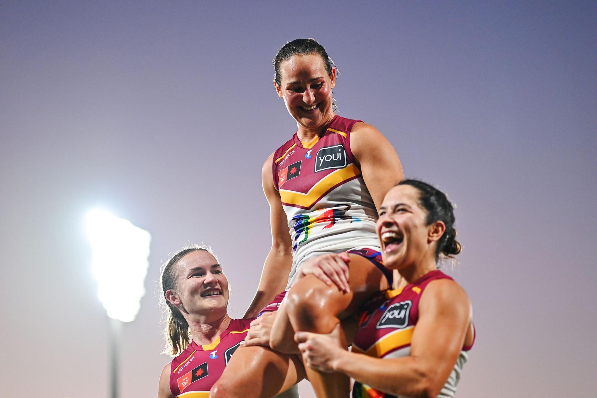 Brisbane Lions' Breanna Koenen is carried off the field by her team-mates after playing her 100th AFLW game