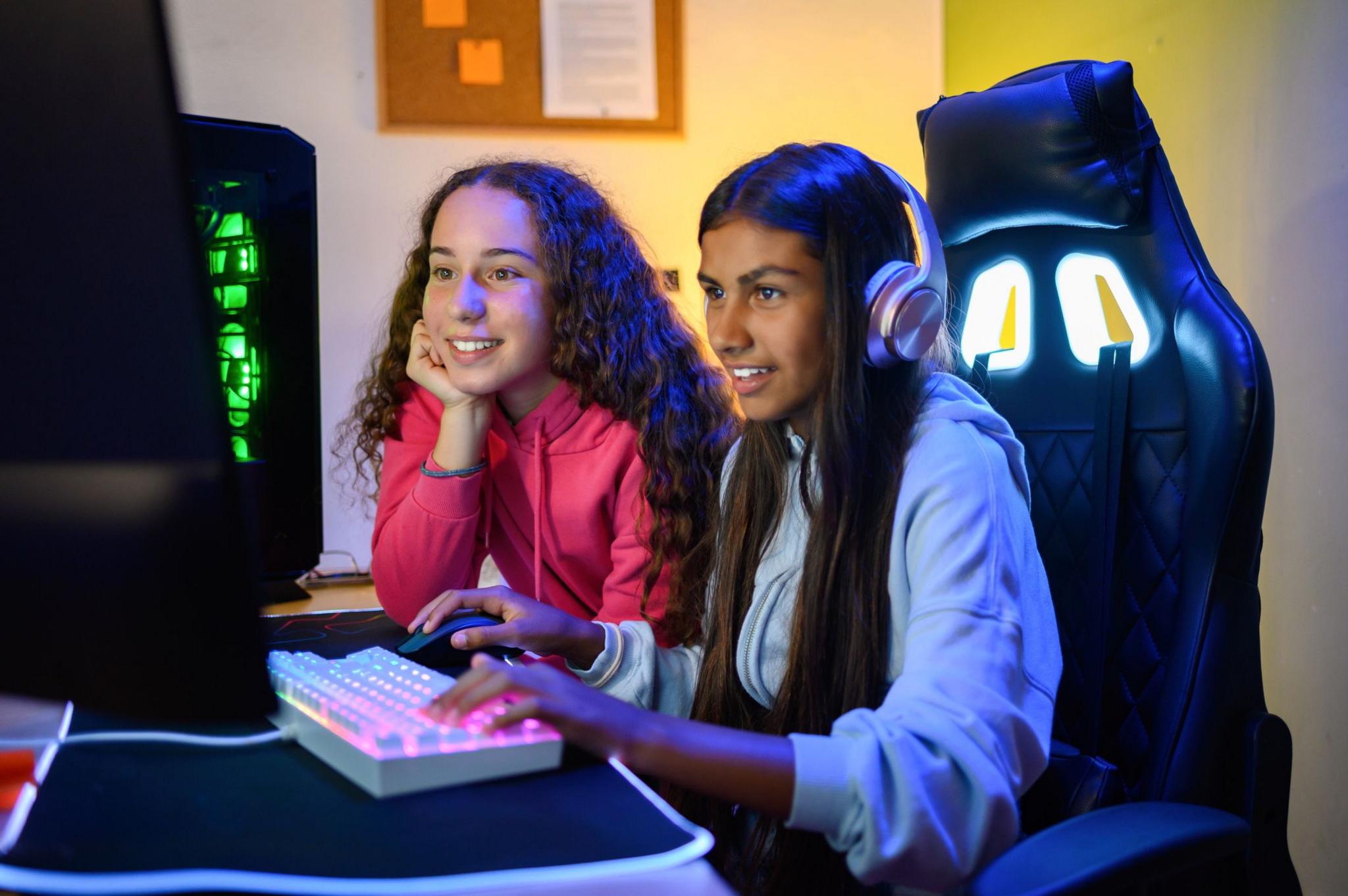 two girls play a video game on a computer