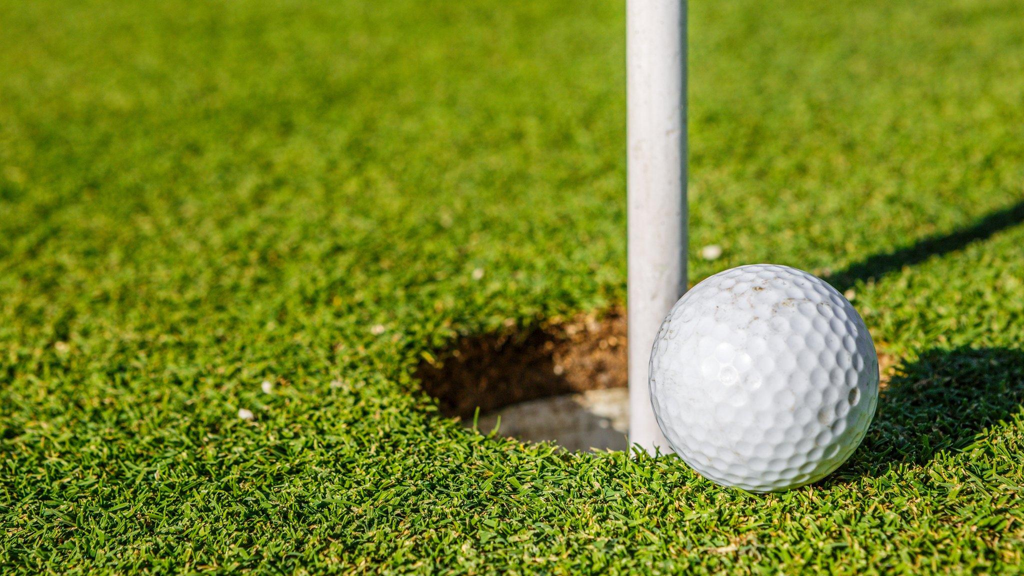 Golf ball next to hole.