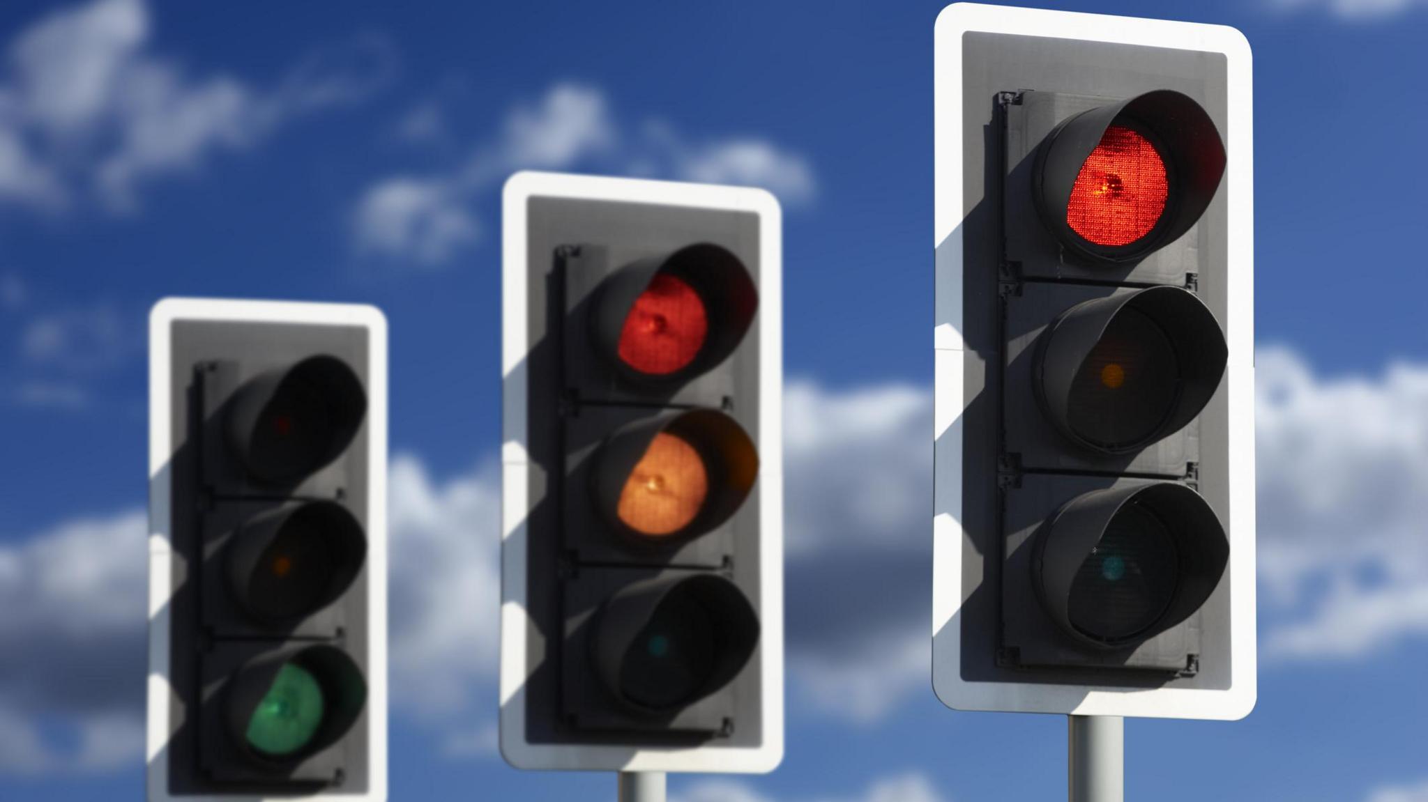 Three traffic lights showing green, amber and red