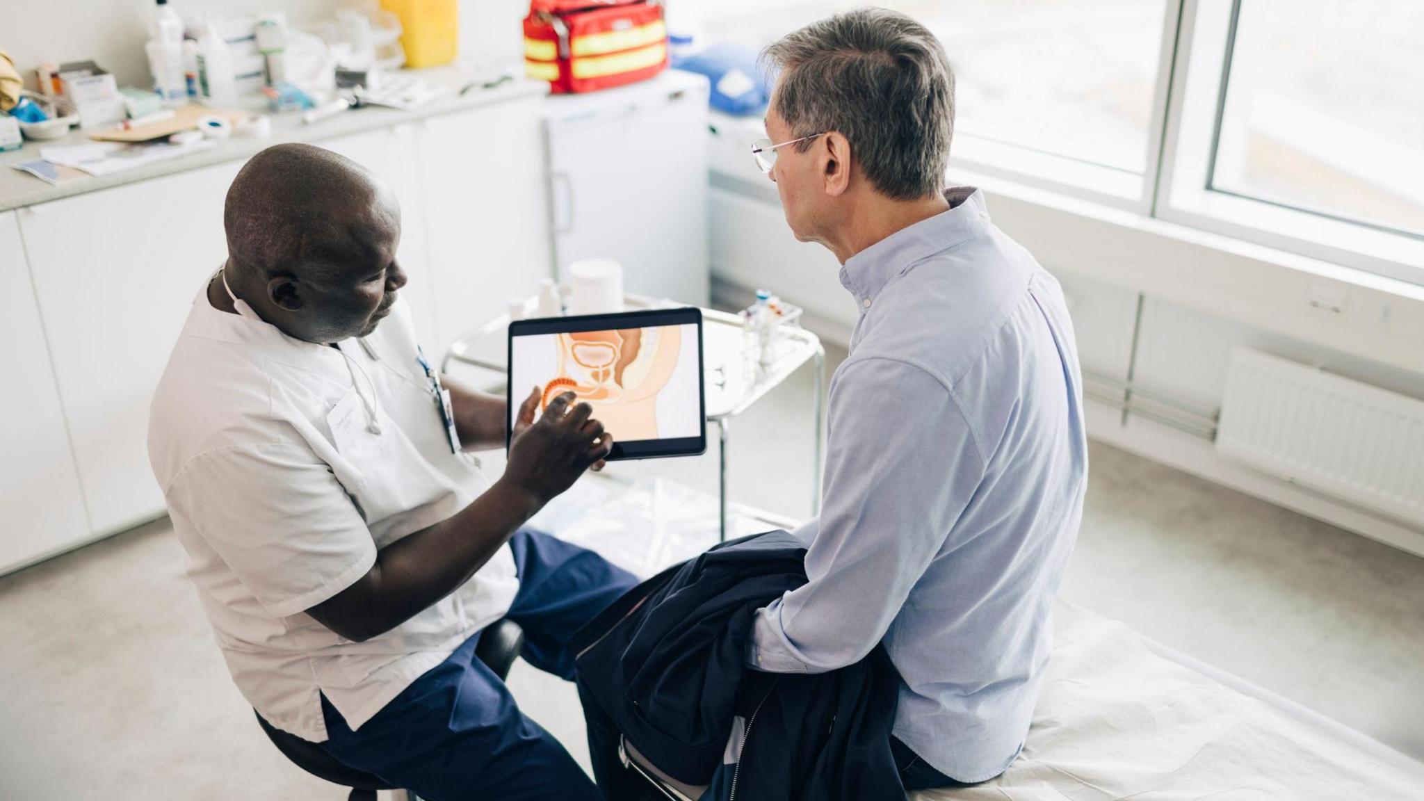 A doctor shows a patient some information on a tablet screen 