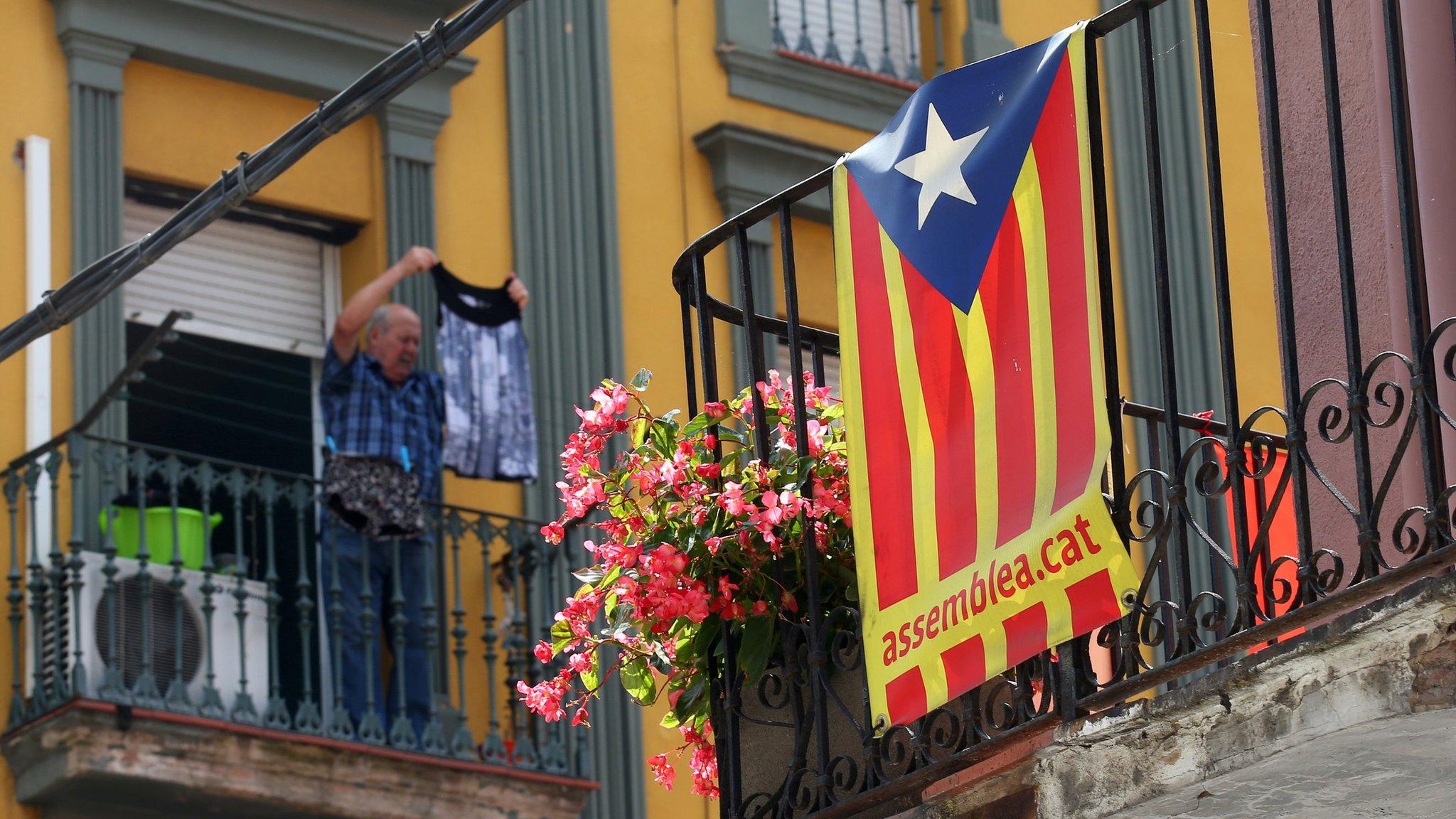 Man hangs clothes in front of a Catalan flag hanging from a balcony in Ripoll, north of Barcelona, August 20, 2017