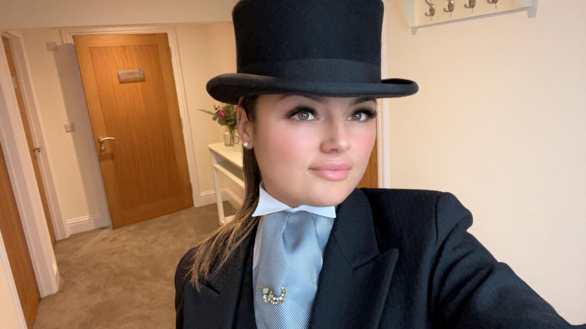 A selfie of a young woman dressed in black funeral attire with black top hat on 