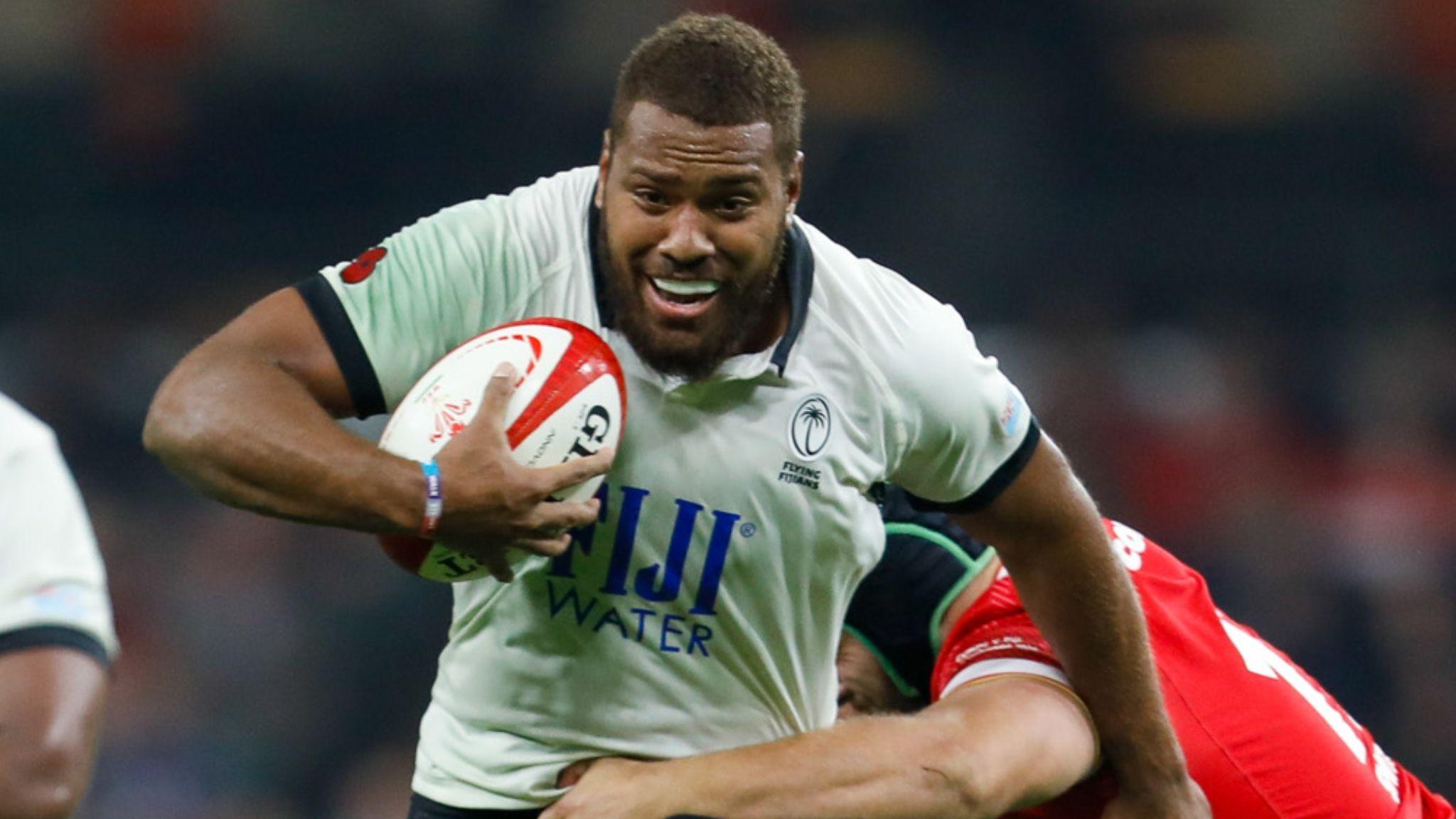Tevita Ikanivere in the white and black of Fiji runs through a Wales tackle
