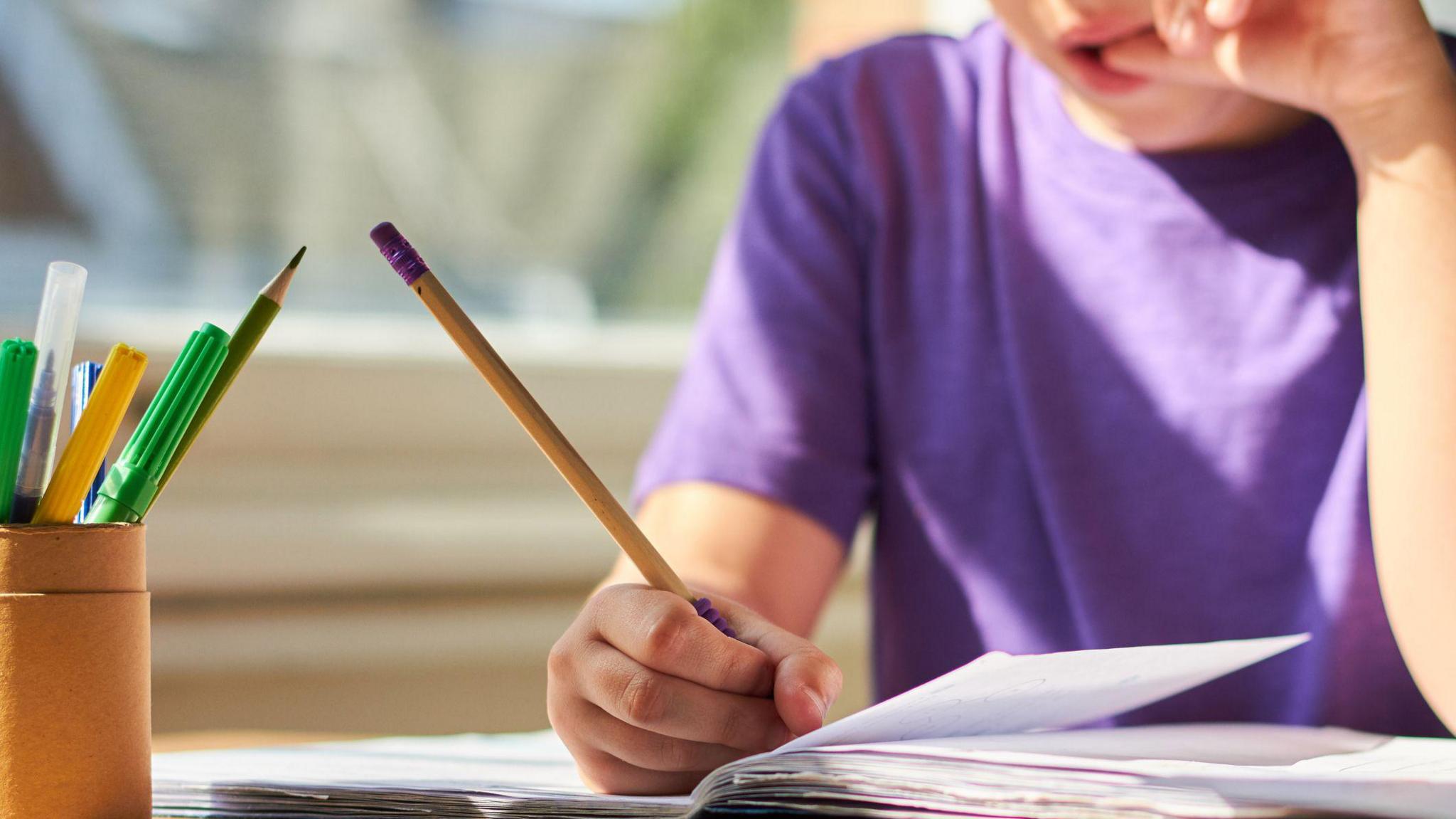 A stock image of a child sitting at a desk doing homework.