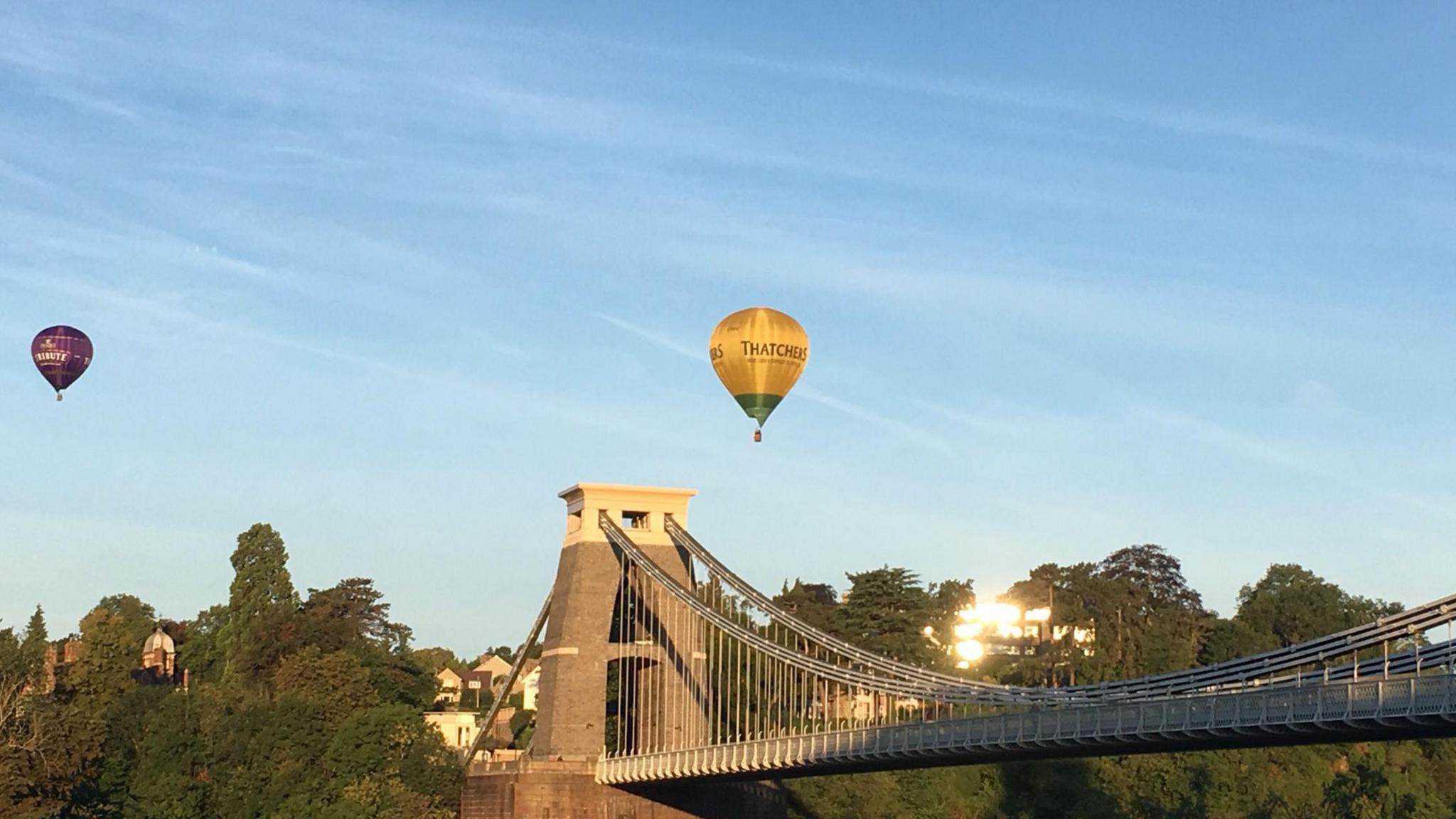 Two balloons floating over Clifton Suspension Bridge as the run rises.