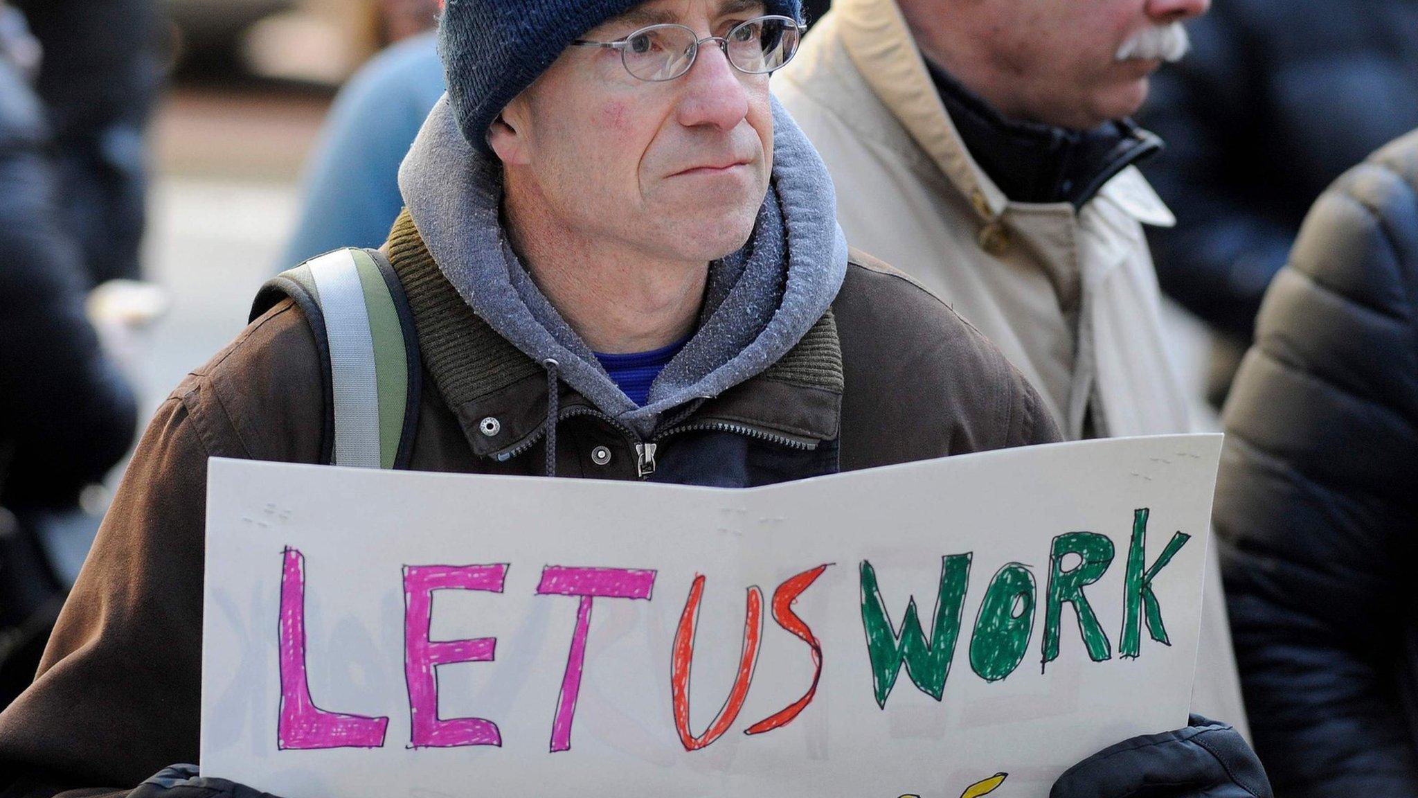 A demonstrator holds a sign during a protest rally by government workers and concerned citizens against the government shutdown