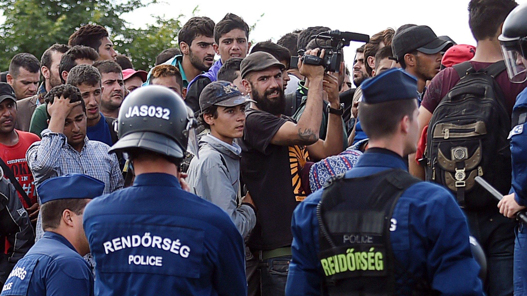 Refugees of different countries are stopped by Hungarian police officers as they walk on the railway tracks near Szeged town after they broke out from the migrant collection point on September 8, 2015.