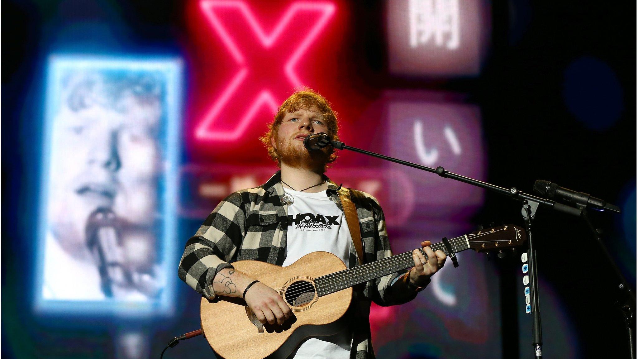 Ed Sheeran playing a guitar on stage