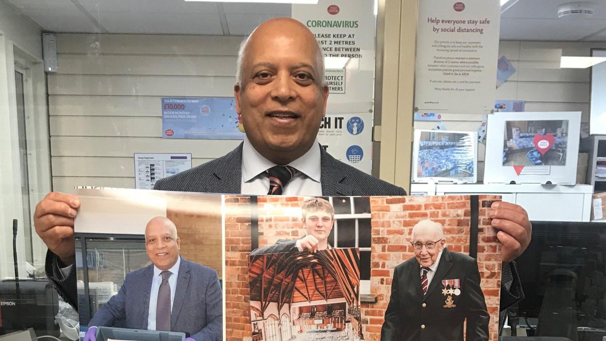 A postmaster in his post office holding a collage which includes pictures of himself and Sir Captain Tom Moore.