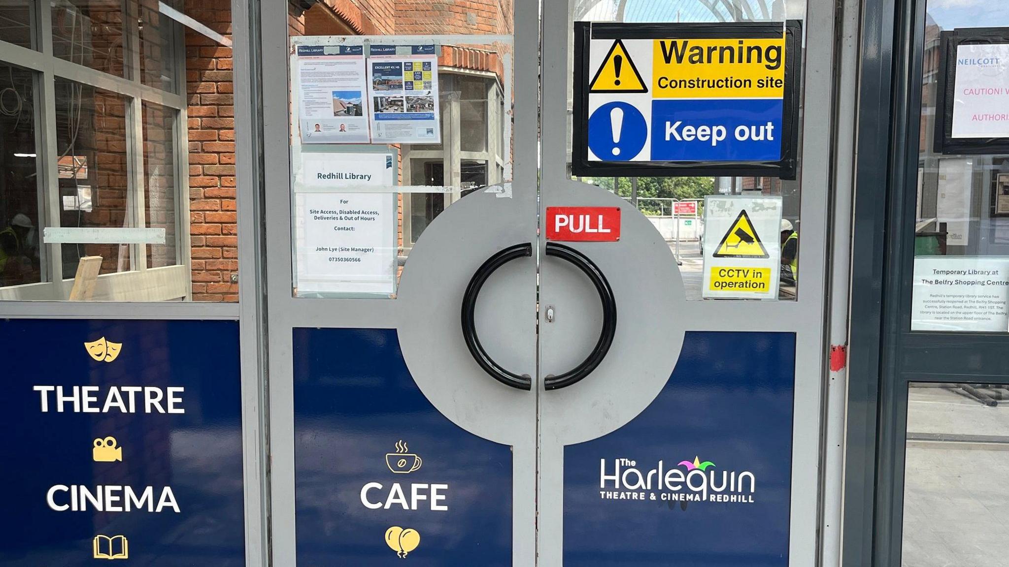 The main entrance to the Harlequin Theatre in Redhill, showing a sign telling people to keep out due to it being a construction site.