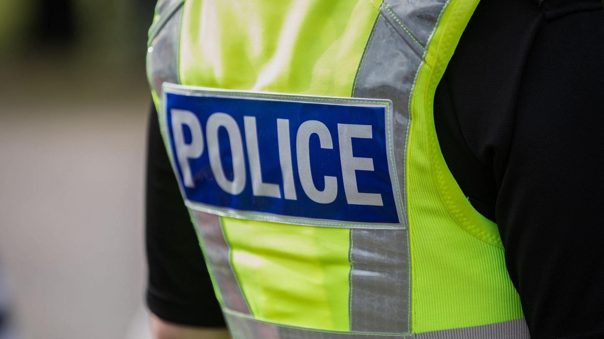 A close up of a police officer wearing a high vis police vest