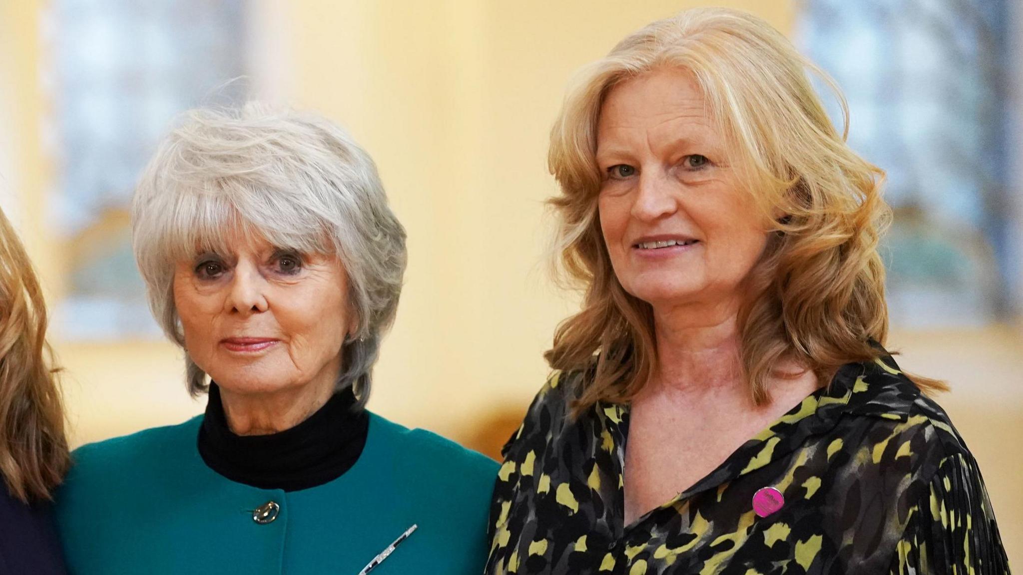 Diana Parkes, a women with grey hair and wearing a teal top, and Hetti Barkworth-Nanton, a blonde woman wearing a yellow and black blouse, looking straight at the camera.