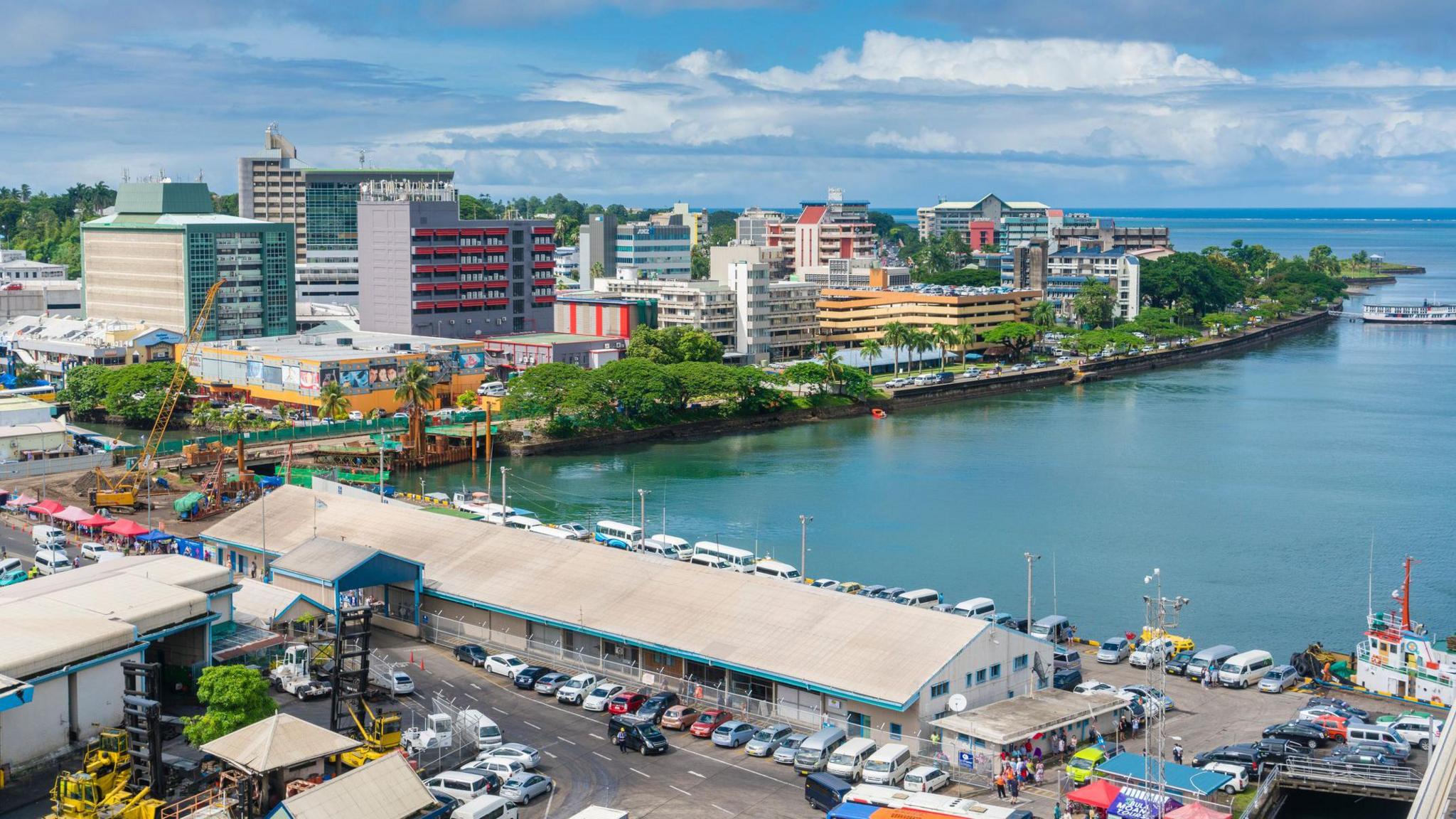 A view of the Suva waterfront, with a dock in the foreground and multi-storey buildings in the background
