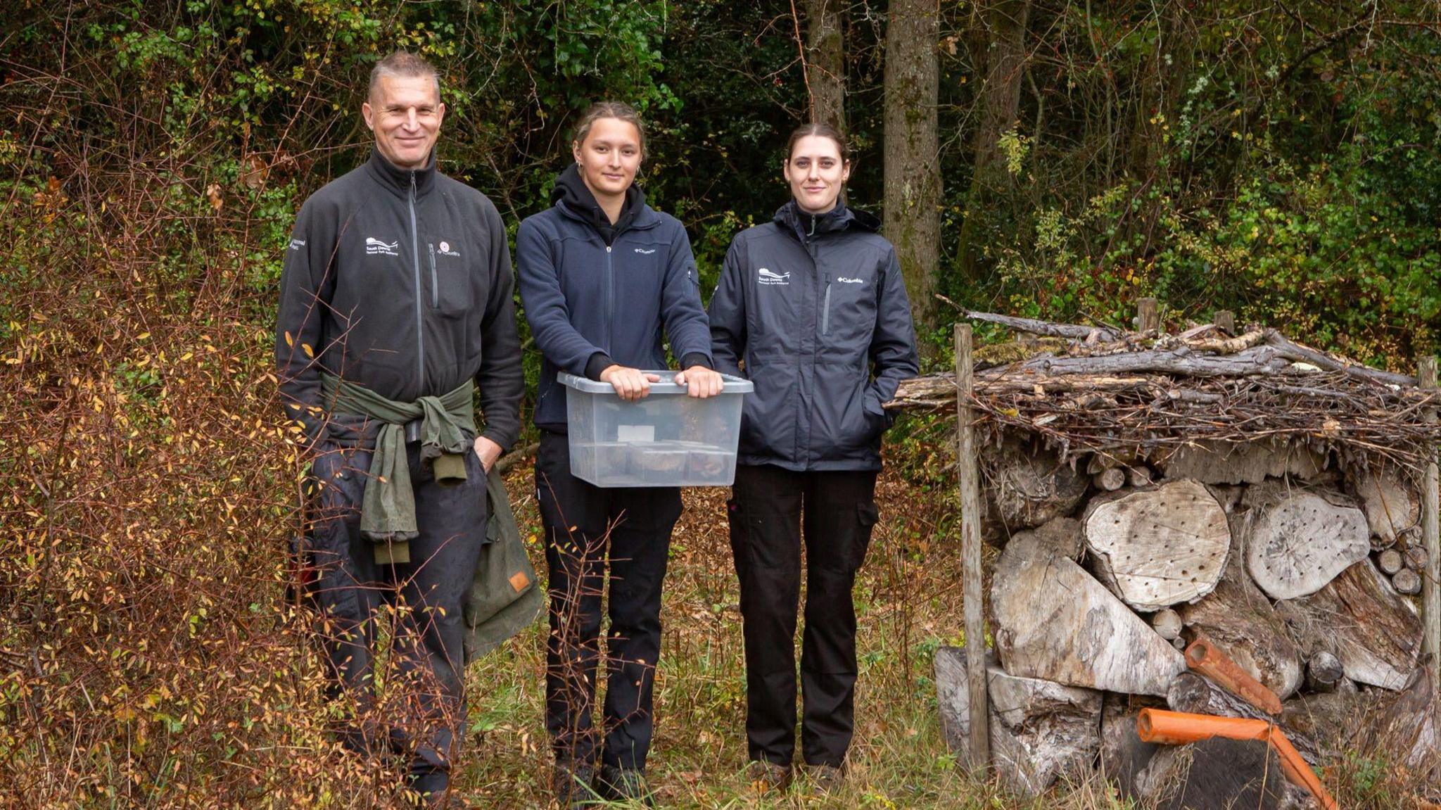 Conservationists and rangers releasing the glow-worms, they are smiling at the camera.