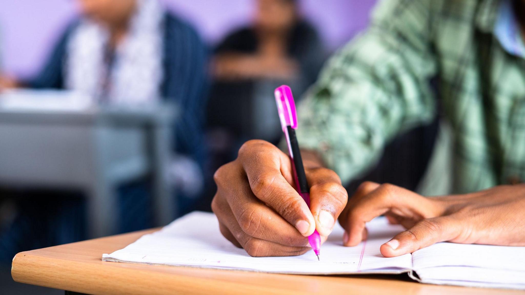 Close up shot of a student's hand writing in a notebook