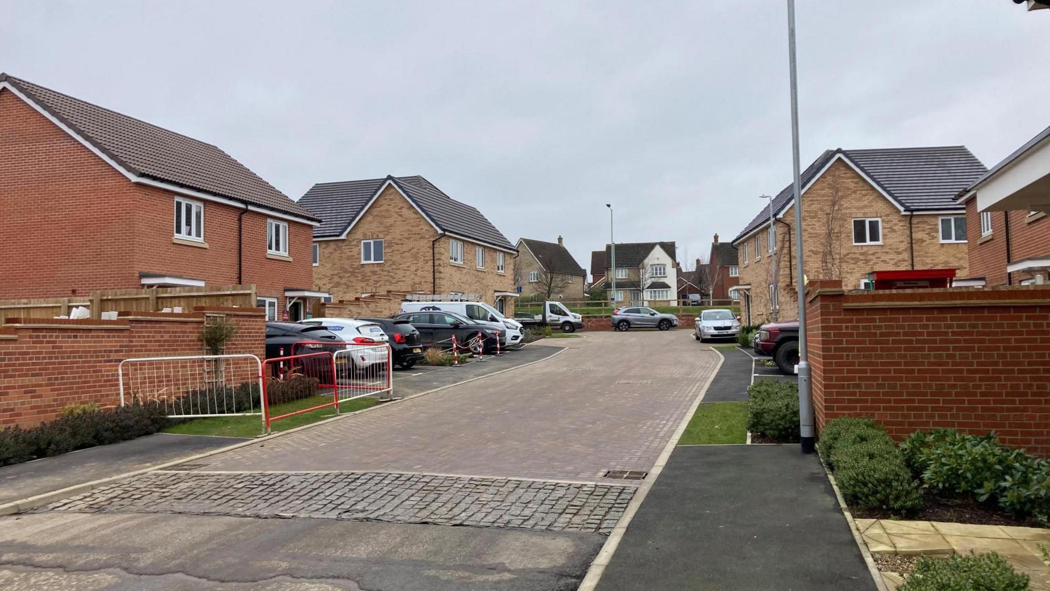 The entrance to a cul-de-sac, with numerous homes and cars.