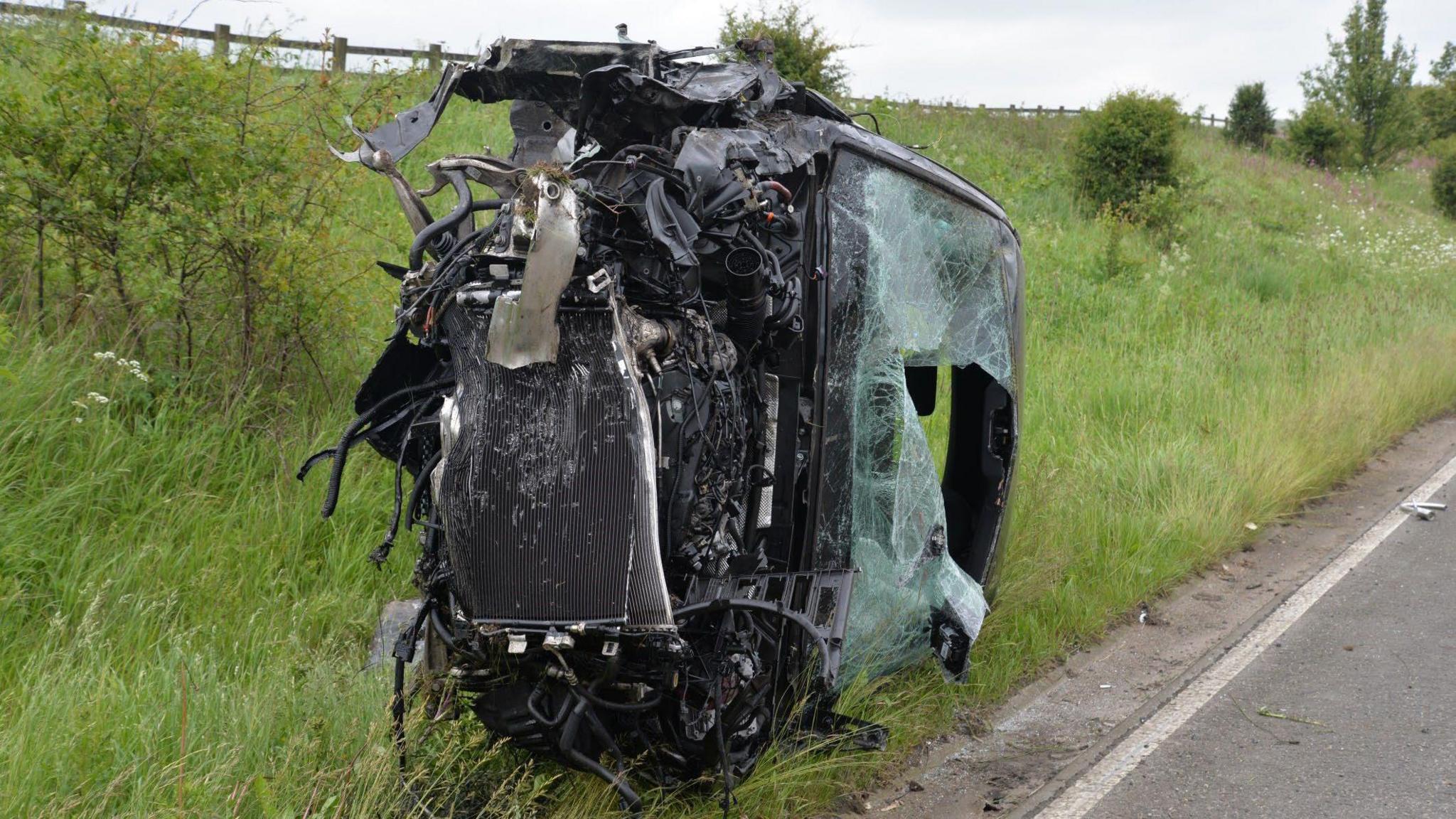 A car on its side and desteriyed beyond all recognition