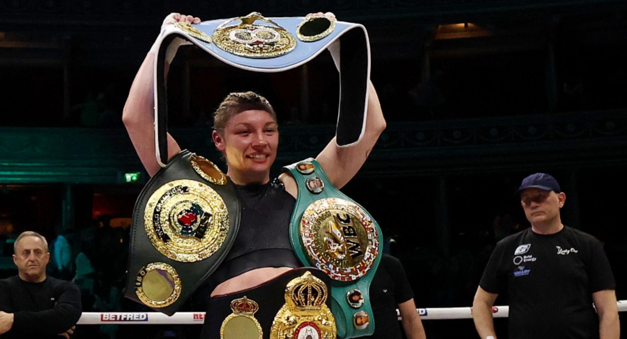 Lauren Price holds her world title belts in the ring