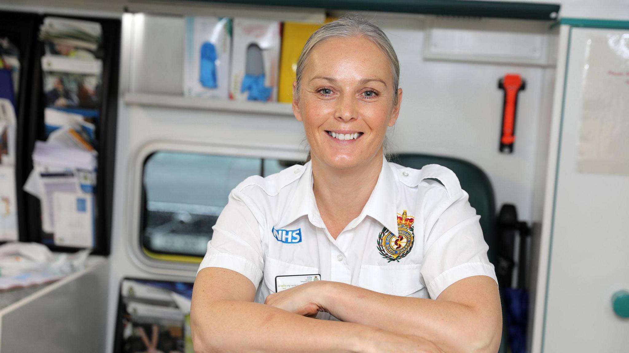 A woman in ambulance uniform, smiling at the camera.