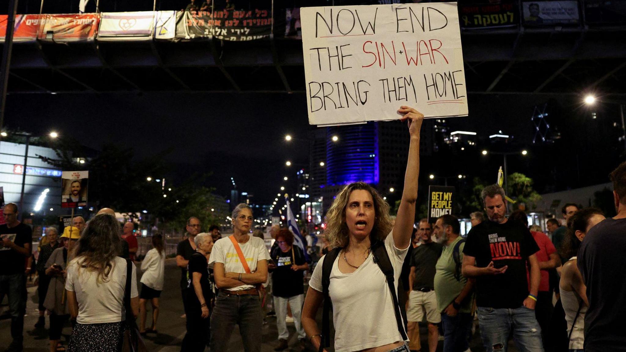 A demonstrator holds a sign with a reference to Hamas leader Yahya Sinwar, in Tel Aviv