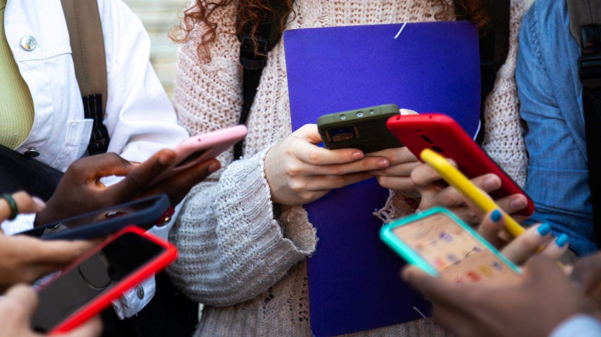 Various teenagers all holding mobile phones