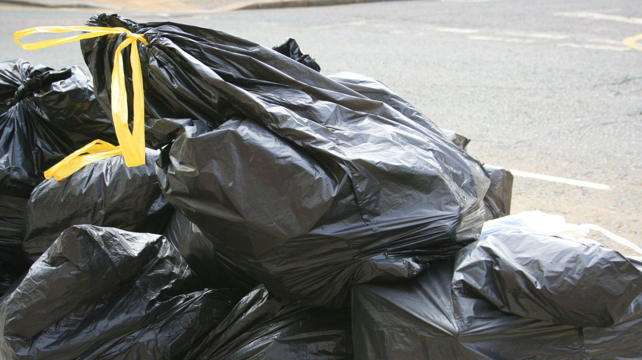 Black bin bags on the side of the street