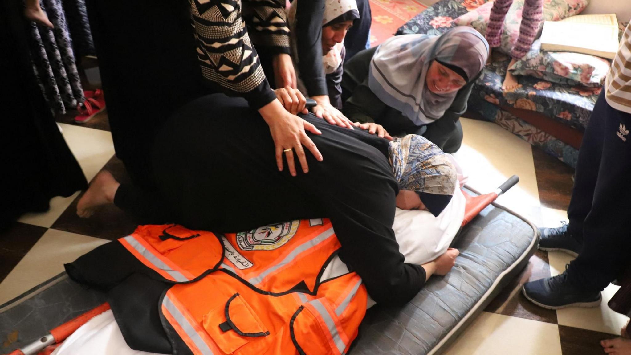 Women mourn over the body of Civil Defence first responder Munther al-Dahshan, who was the agency said was killed in an Israeli strike in Gaza City (1 October 2025)