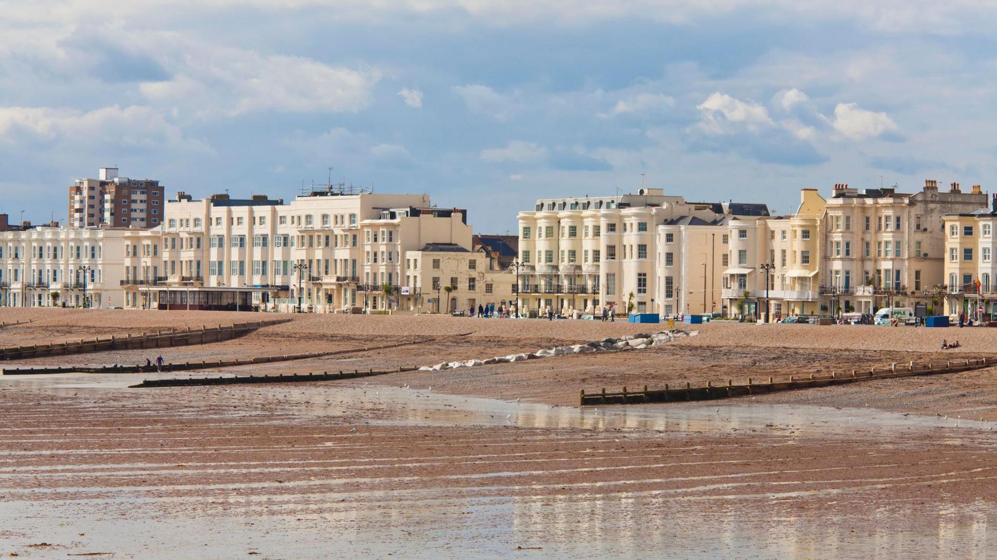 A row of big white houses are visible in the distance with a beach at low-tied in front. 