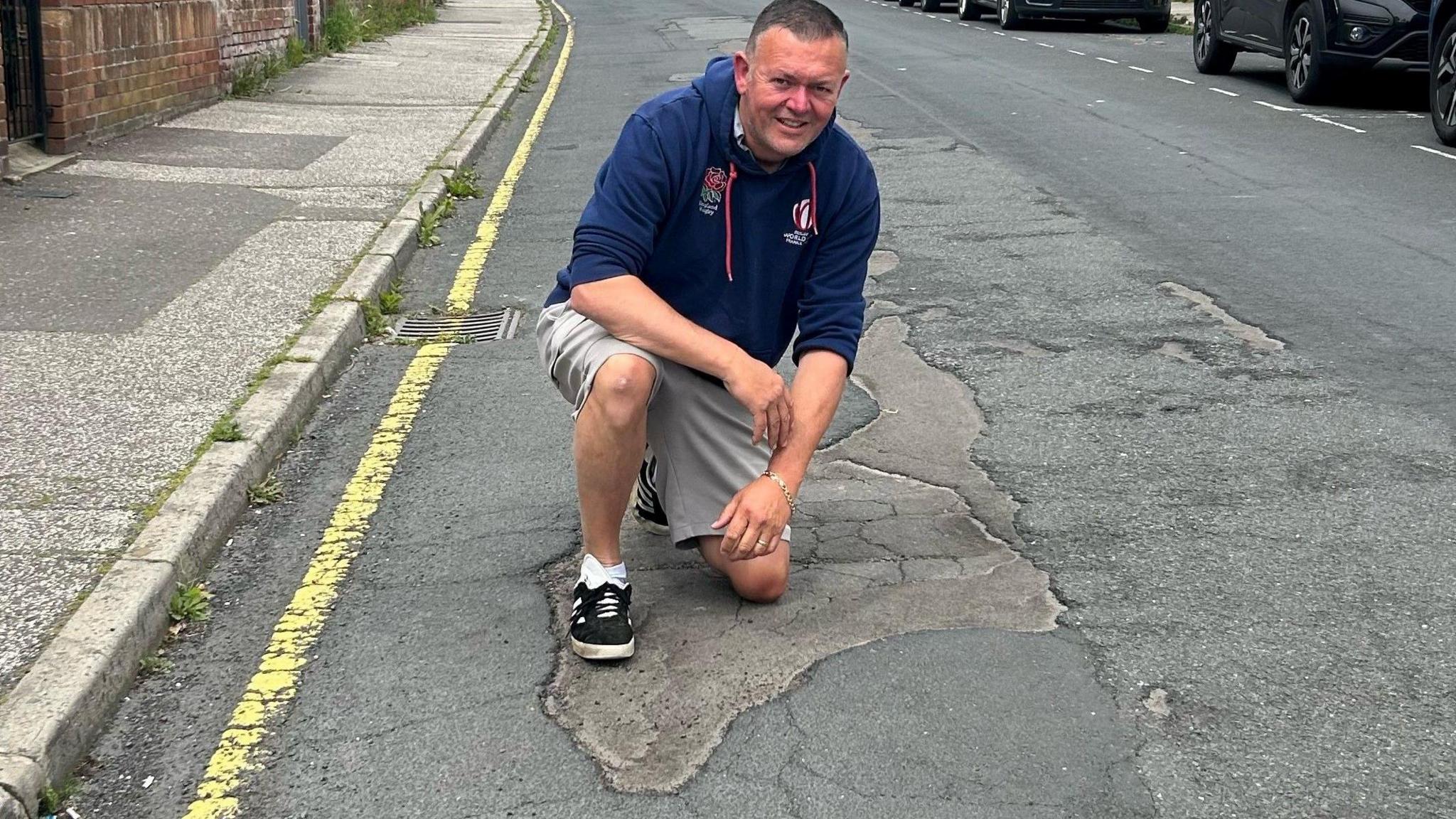 Driving instructor Mark Ritchie posing with a pothole in Suffolk