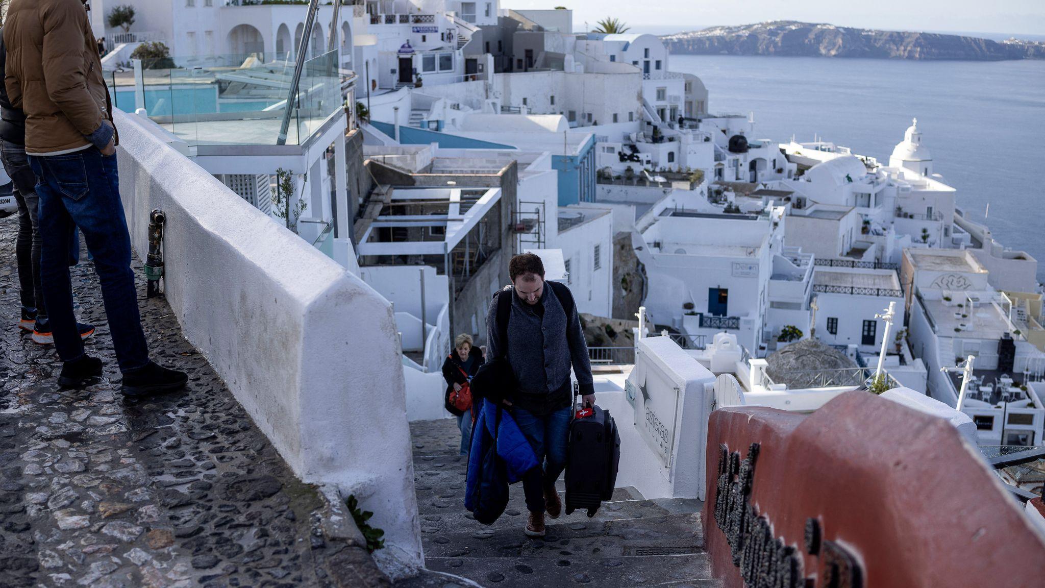 People leaving the Port of Fira carrying a suitcase 