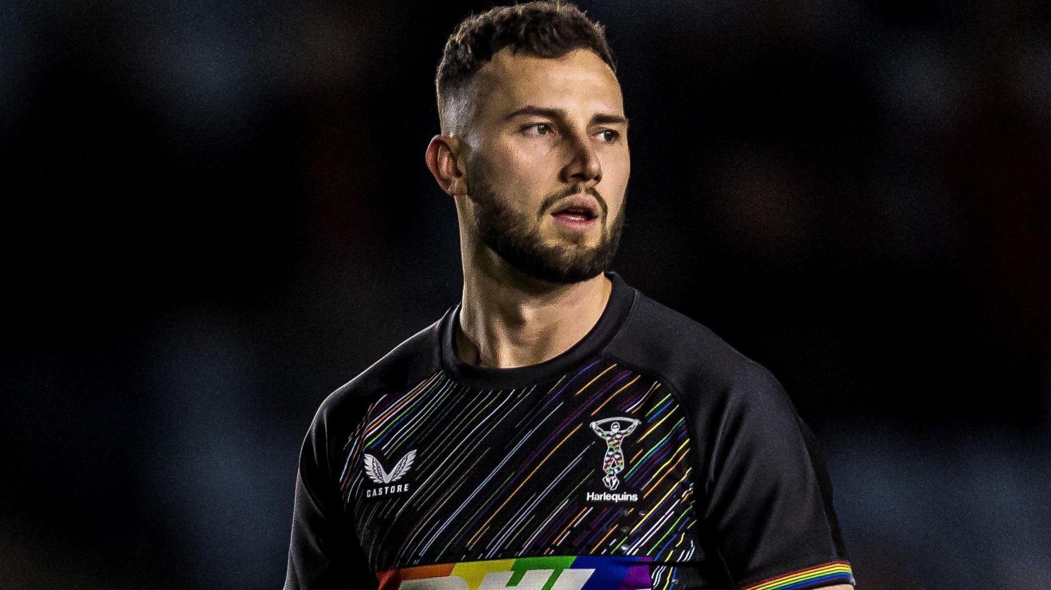 Max Green, wearing Harlequins' black kit with different coloured, diagonal pinstripes