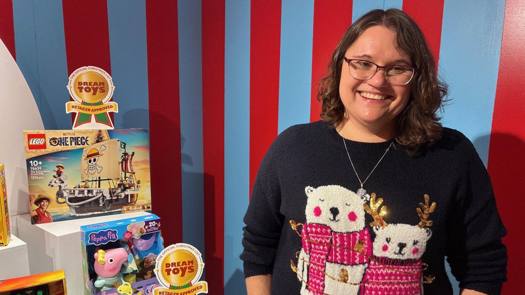 Melissa Symonds stands next to a display of toys and the DreamToys event.