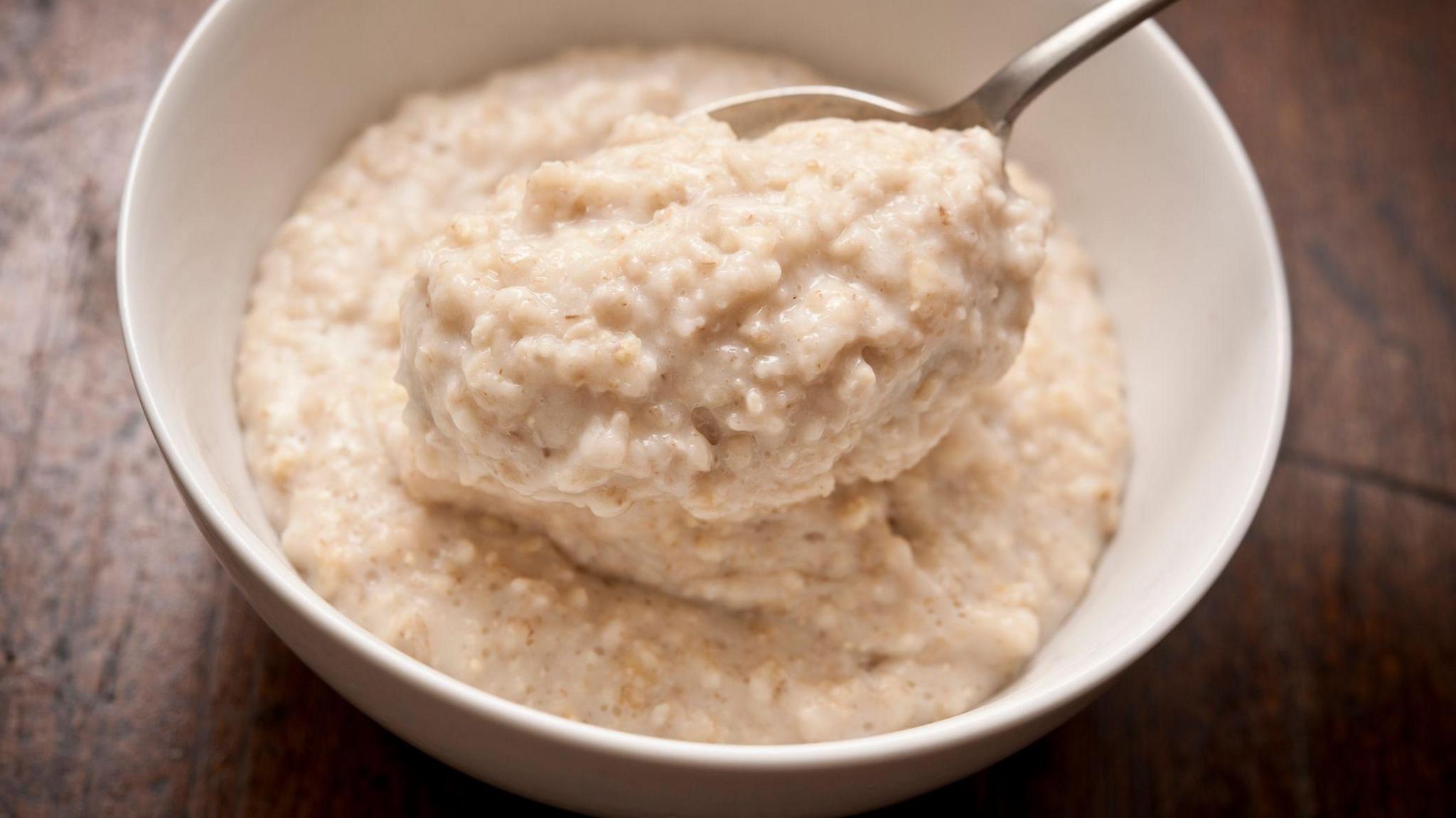 Close-up of a bowl of porridge with a spoon on a wooden table