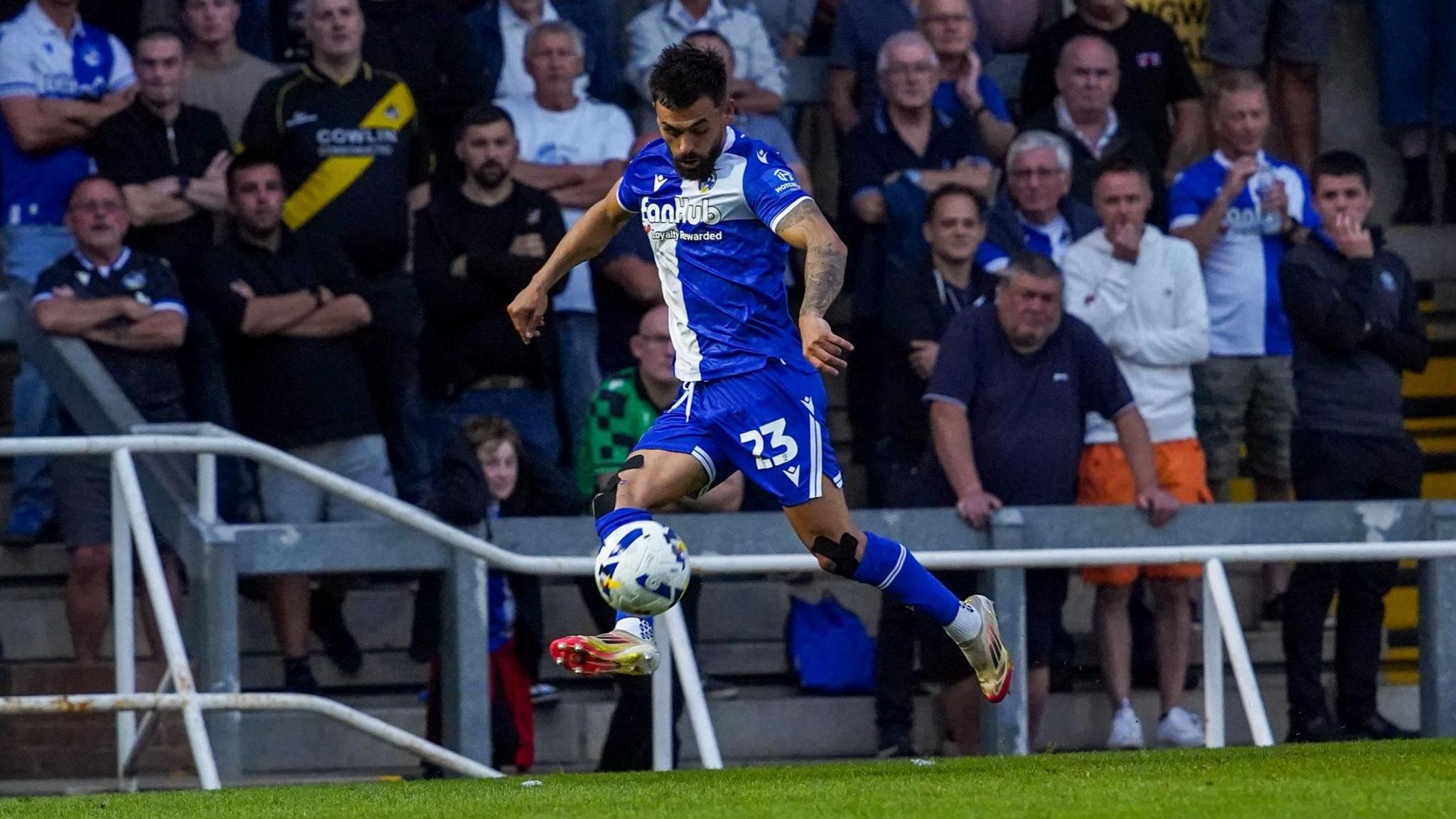 A Bristol Rovers player is airborne as he runs down the wing at the Memorial Stadium in the game against Oldham Athletic. Fans are visible on the terraces in the background