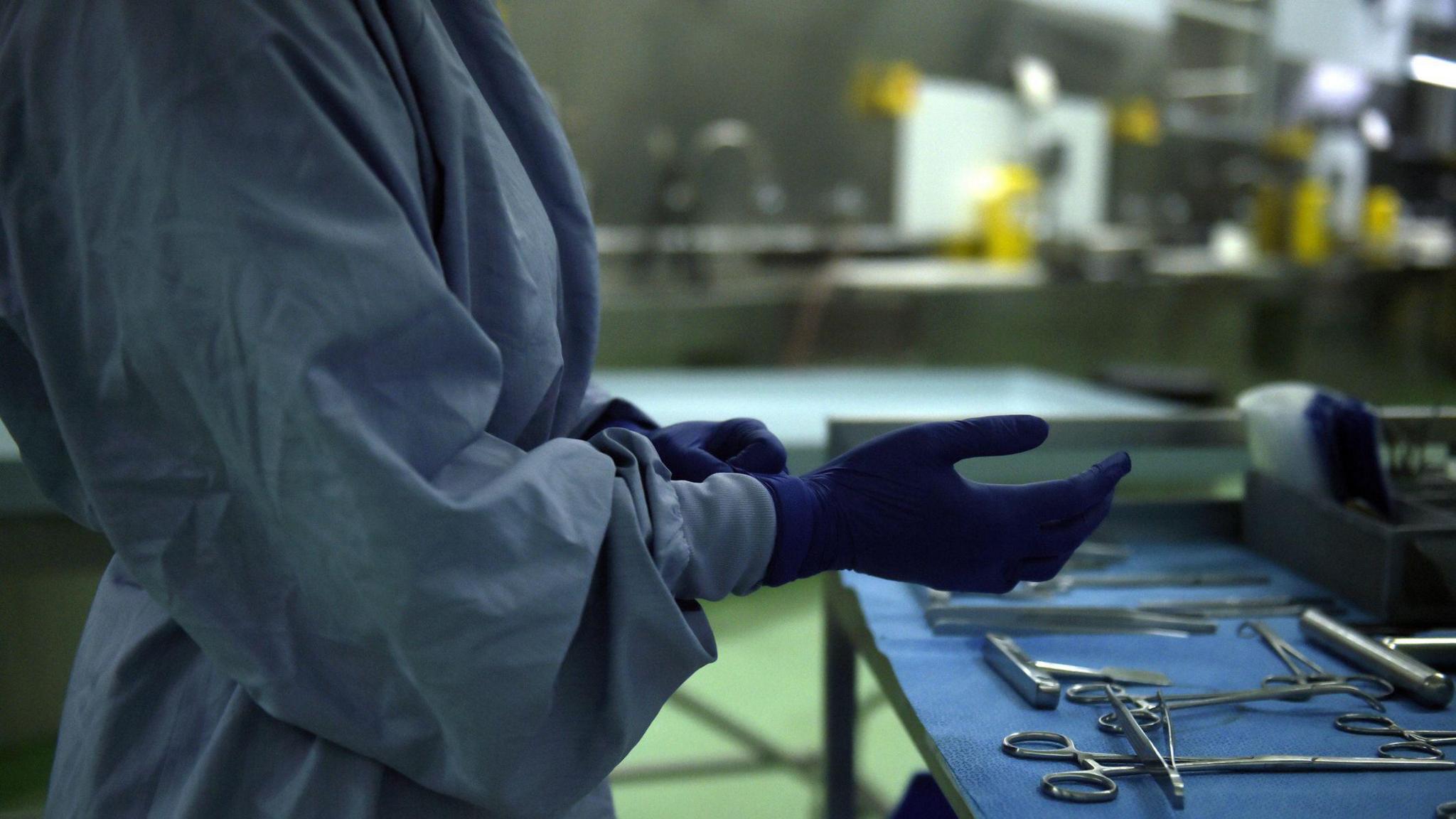 A person in scrubs wearing blue gloves