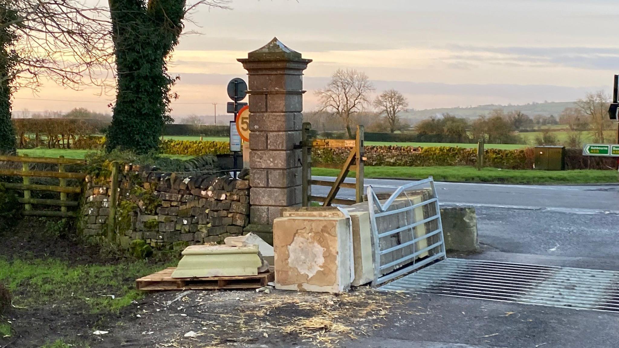 A fallen stone pillar at the gates of Tissington showing the A515 in background. 