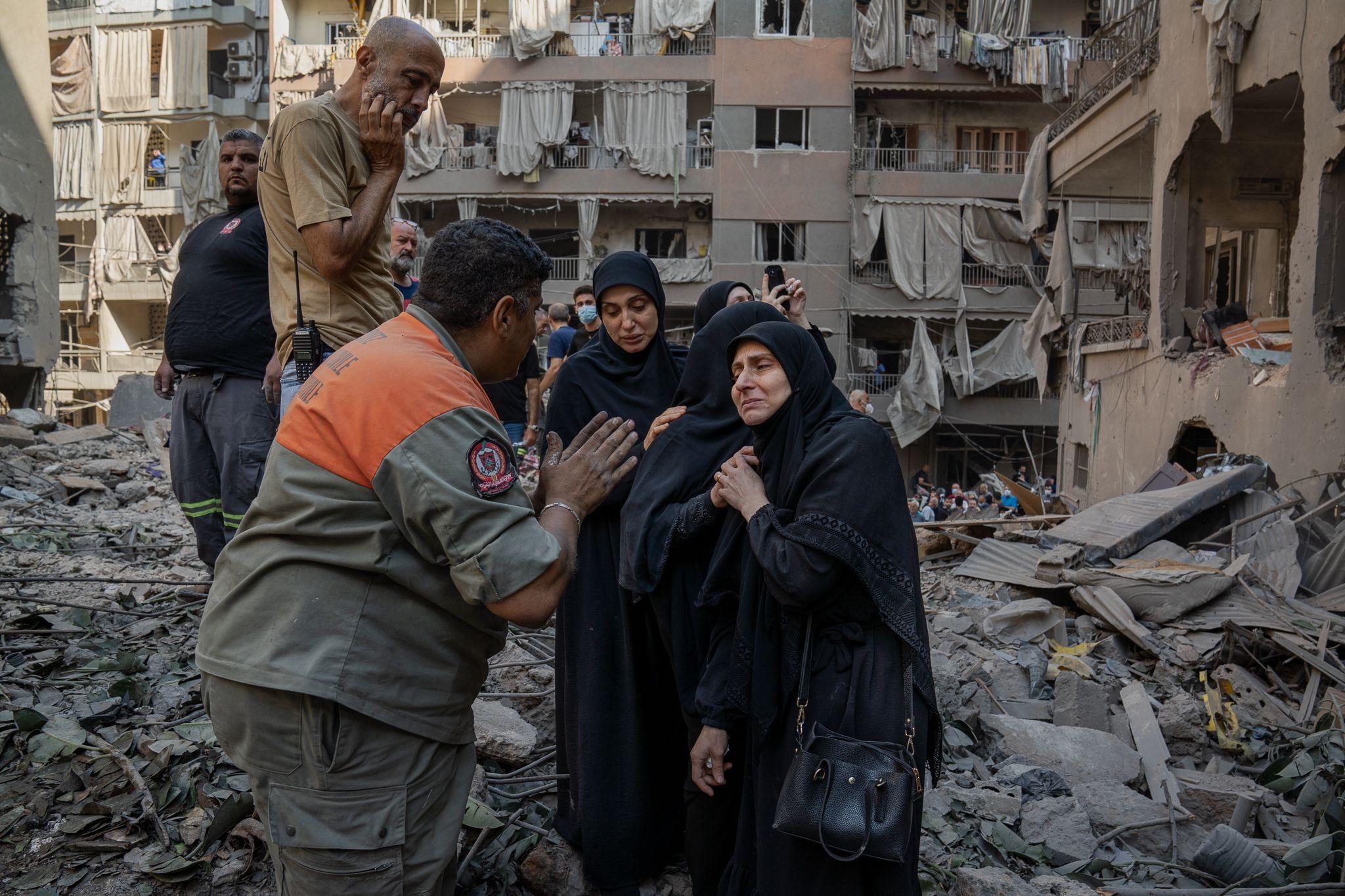 Distraught residents speak to Youssef Al-Mallah, the head of the rescue team, at the site of the Basta strike.