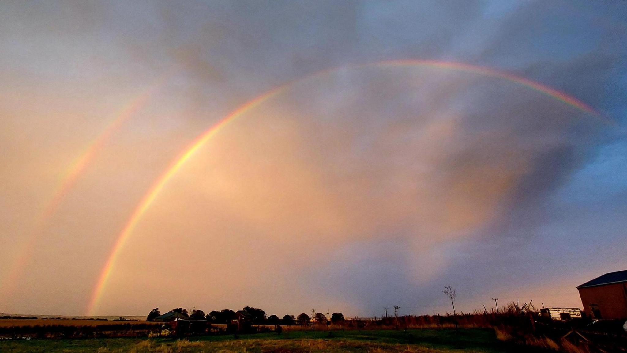 A double rainbow in an orange evening sky over Aberdeenshire.