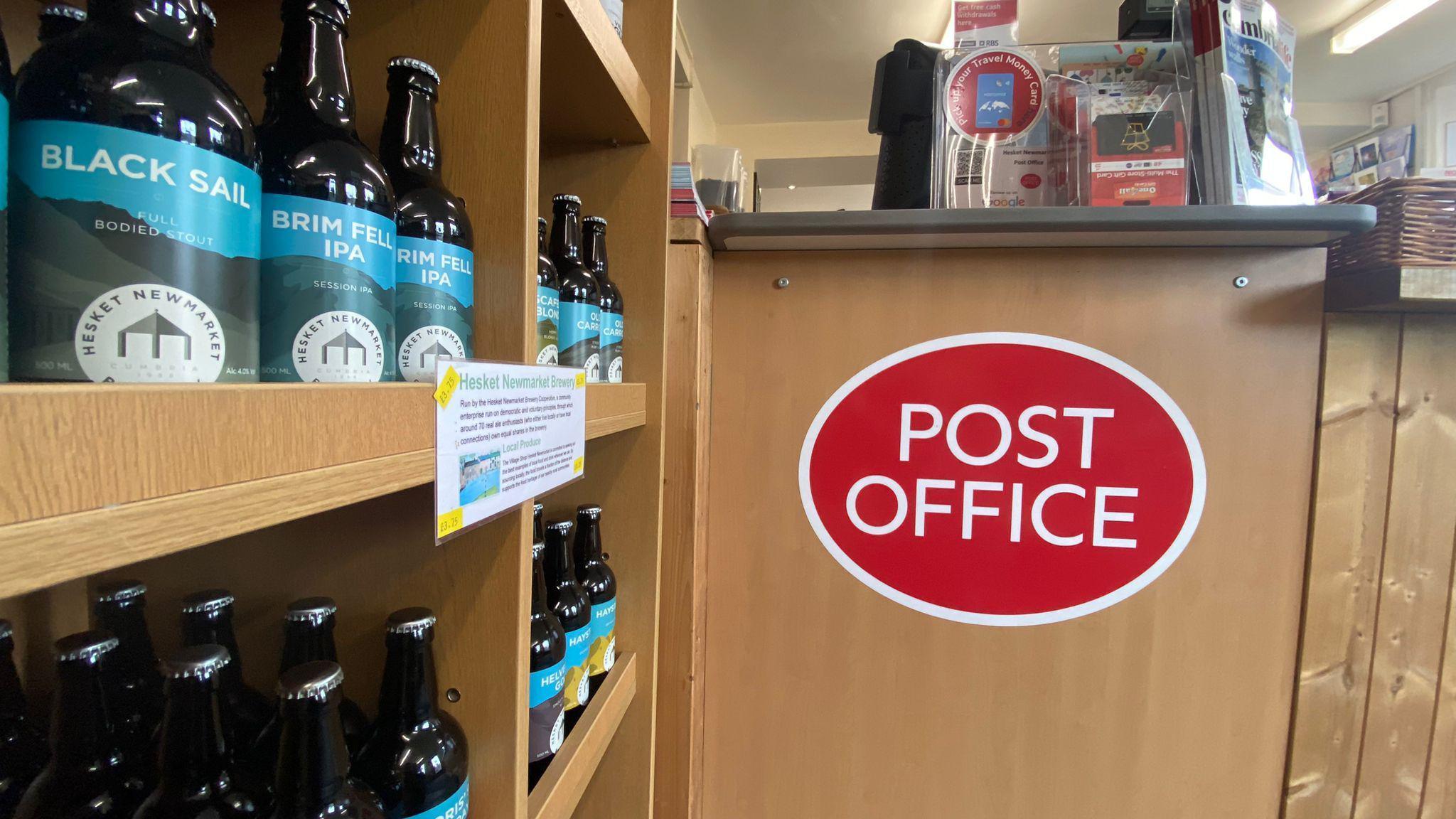 Close up shot of inside the shop with beer on the shelf and a sign for the post office on the wall