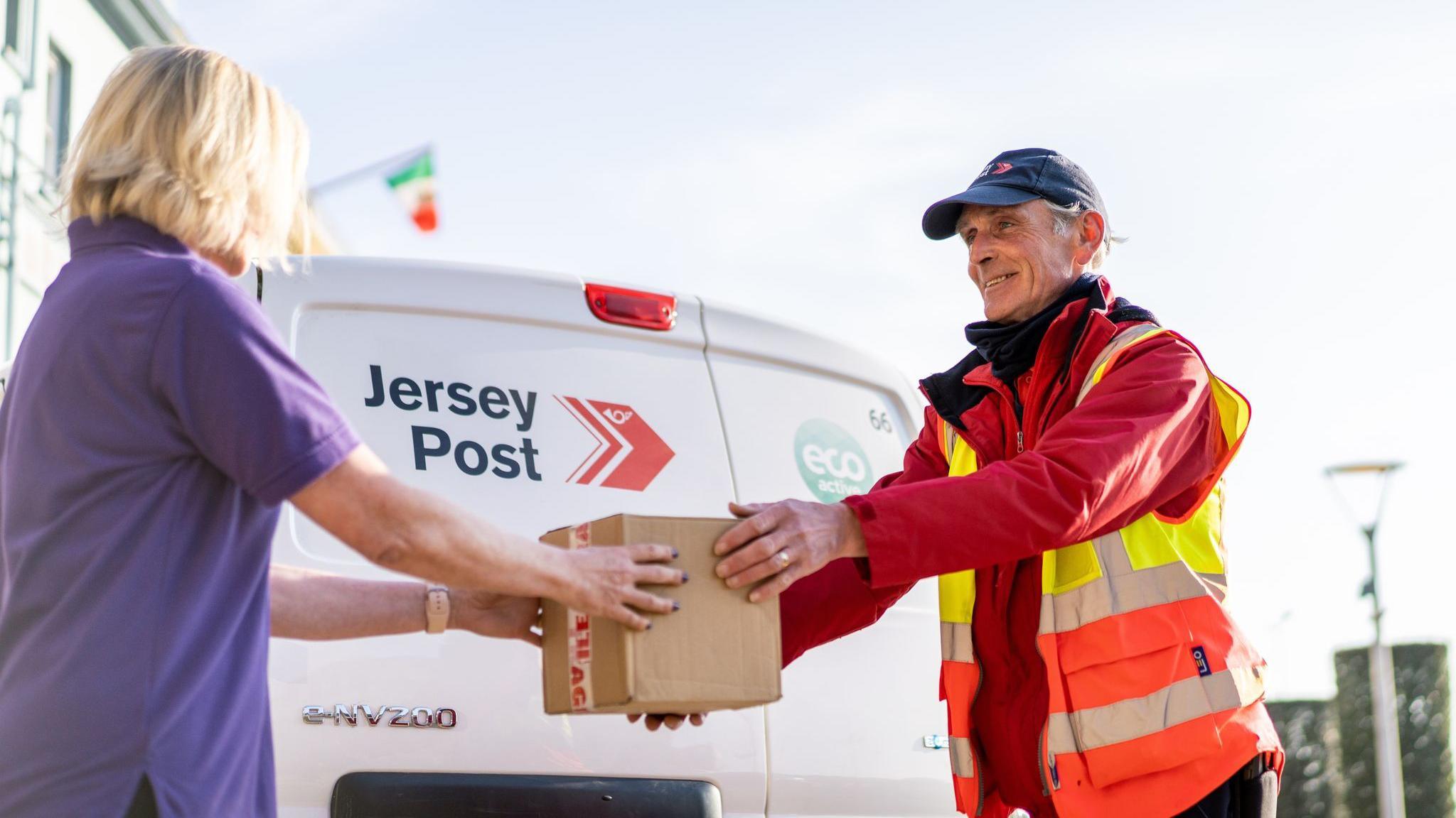 Postal worker giving parcel to person in front of Jersey Post van