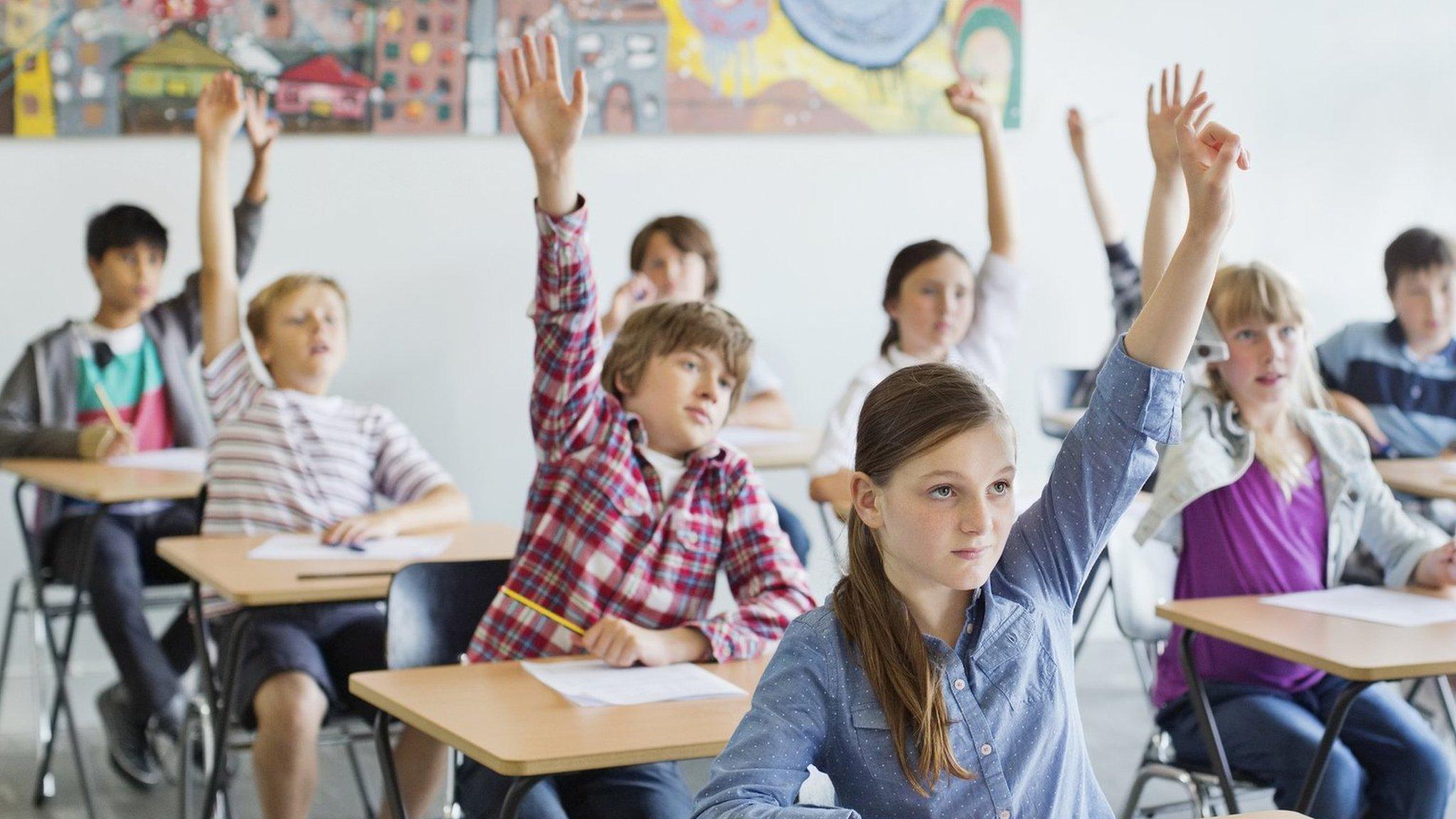 Children in a classroom put their hands up