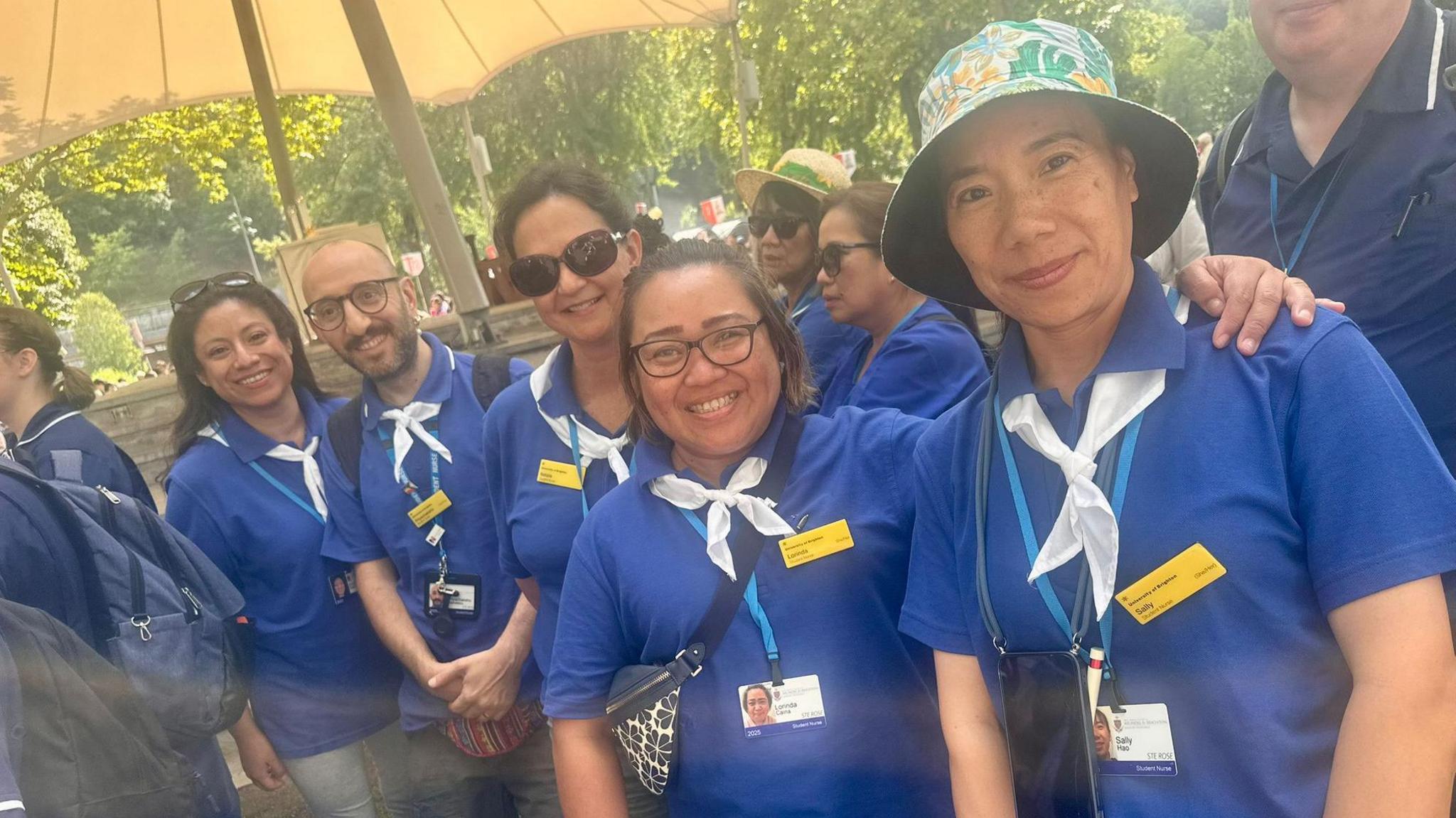 A group of student nurses lined up for the camera wearing blu shorts and white cravats