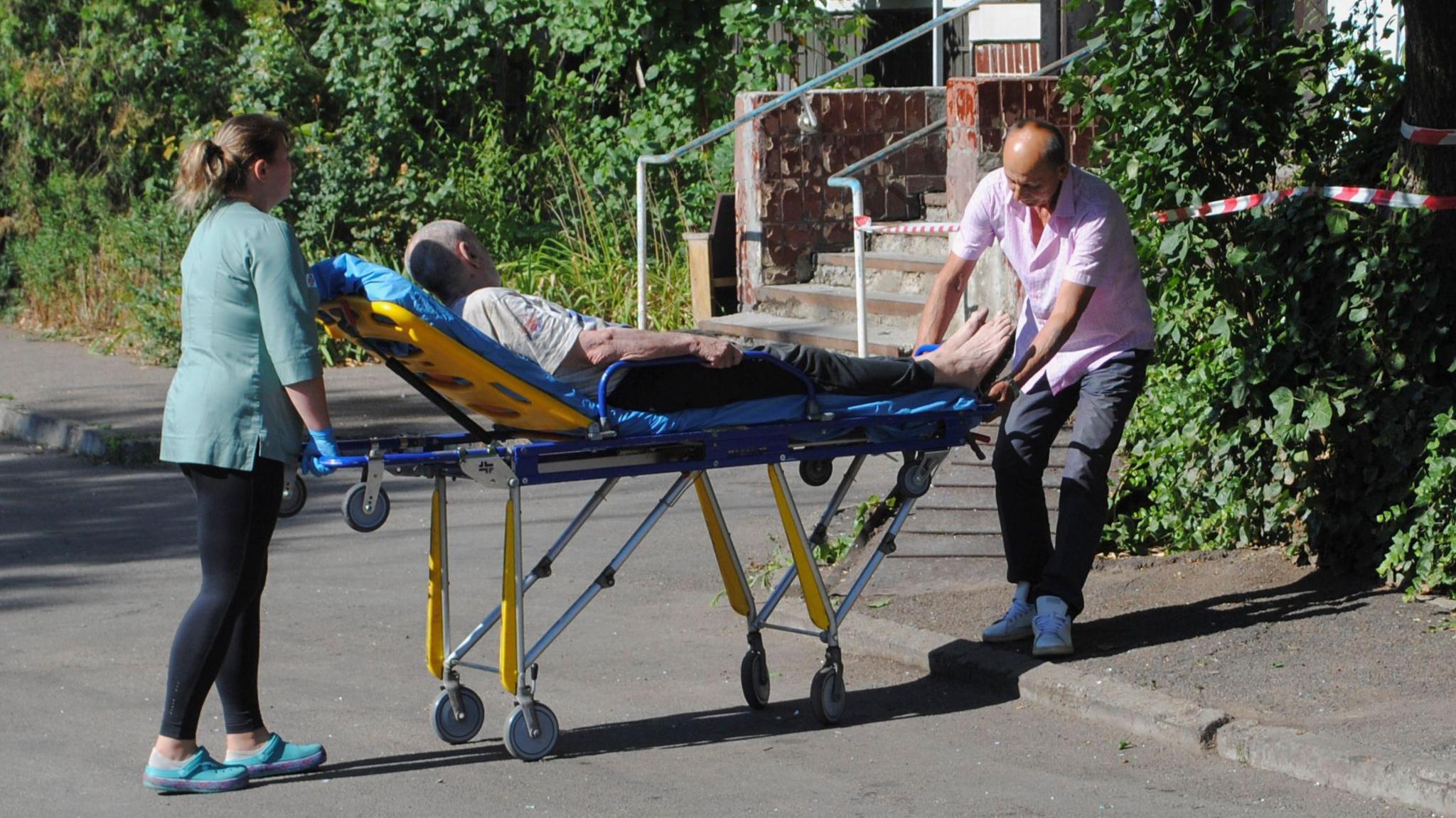 People move a man on a stretcher near a damaged residential building after it was hit in a drone strike in Odesa, Ukraine