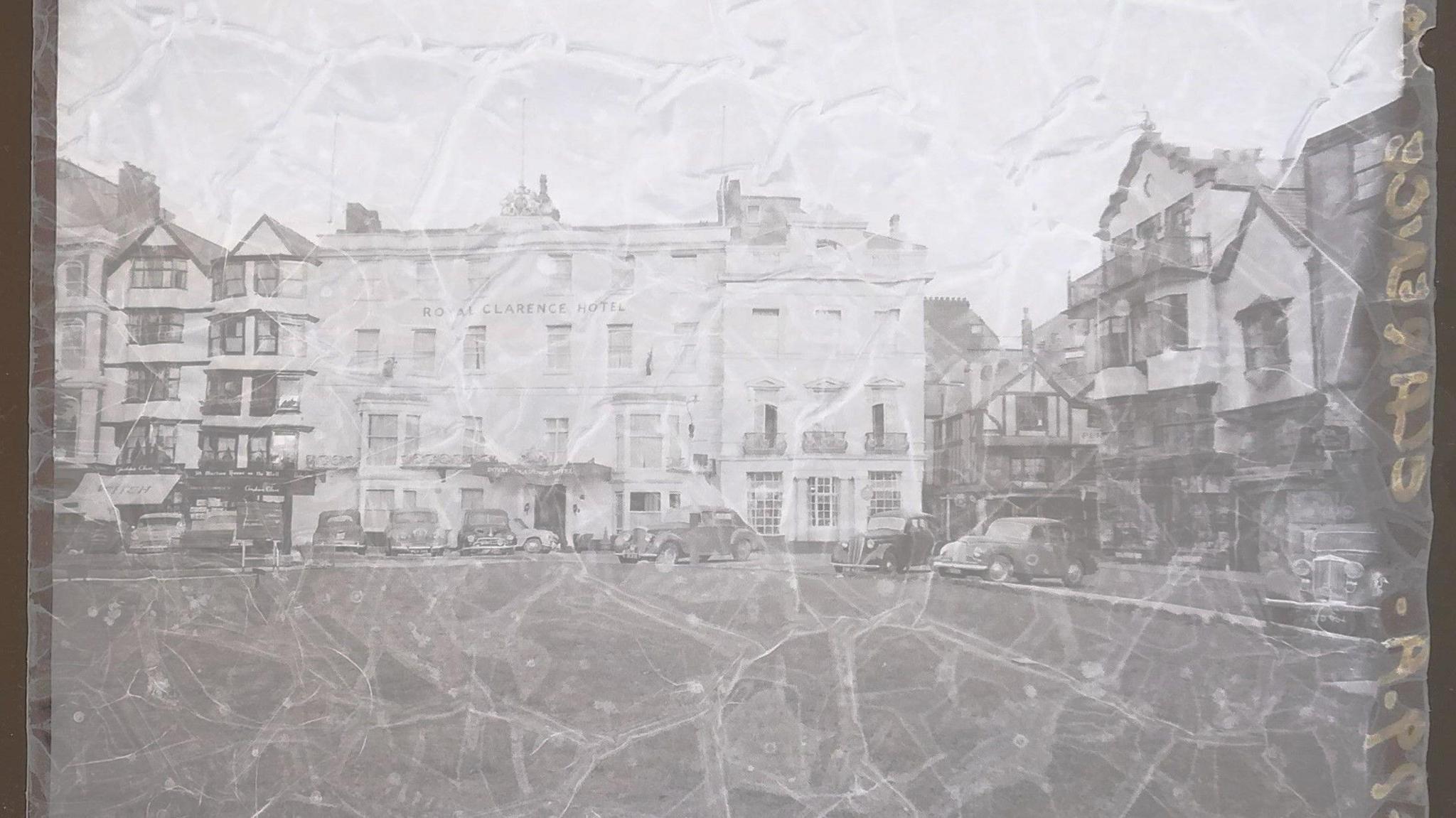 A faded negative of the Royal Clarence Hotel which is showing signs of damage across the image. There is writing in yellow running along the side of the negative.

