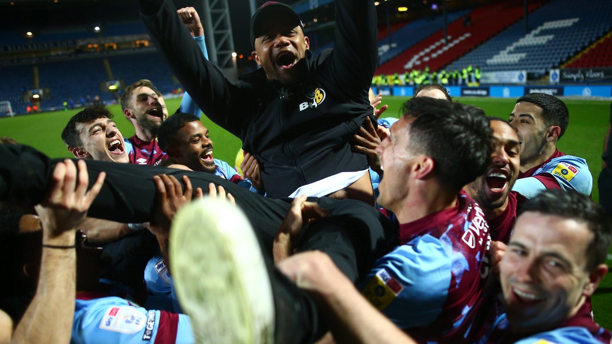 Burnley players hold up Vincent Kompany