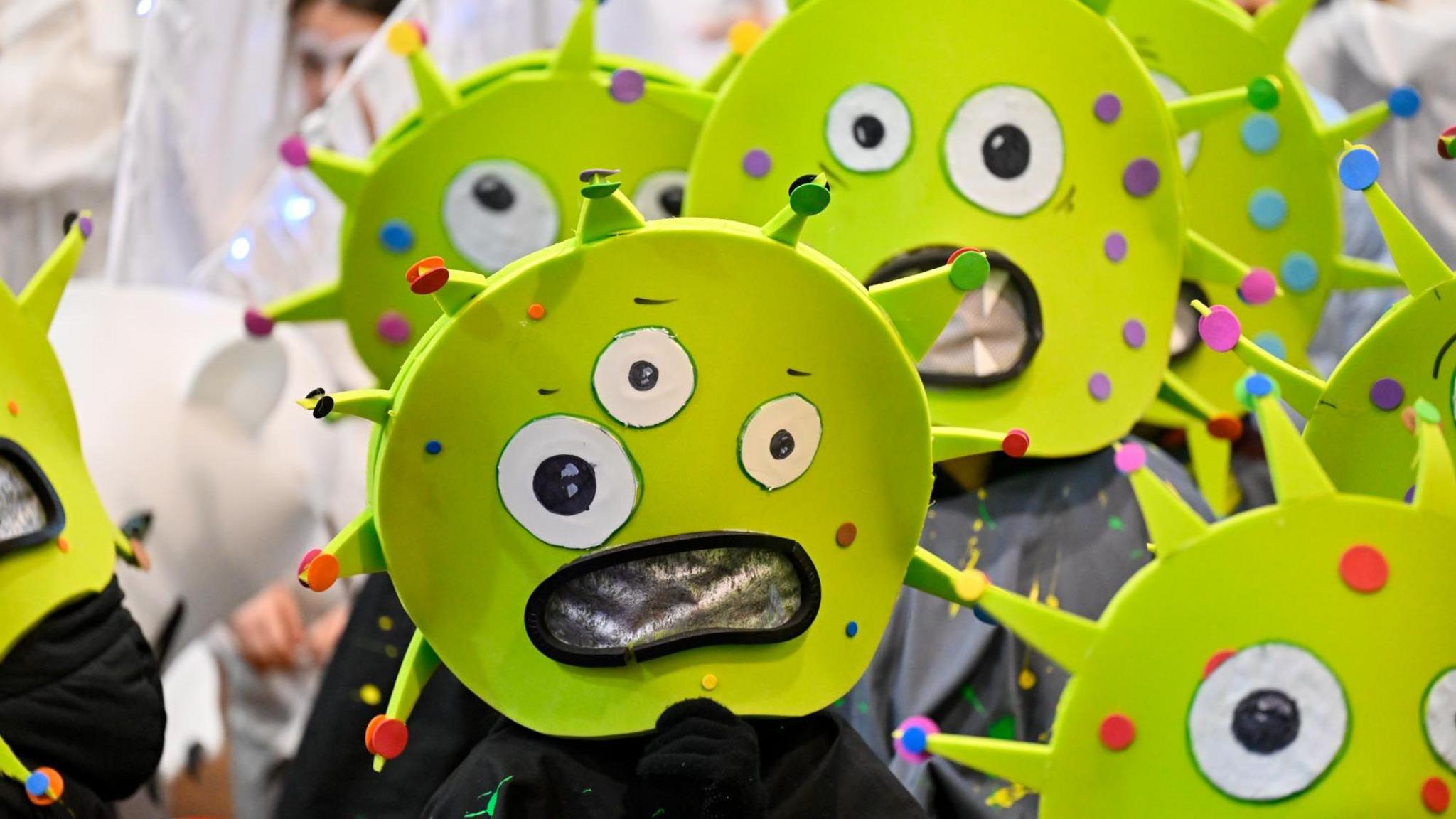 A group of people in green alien masks with big bug eyes on them parade through Dumfries town centre