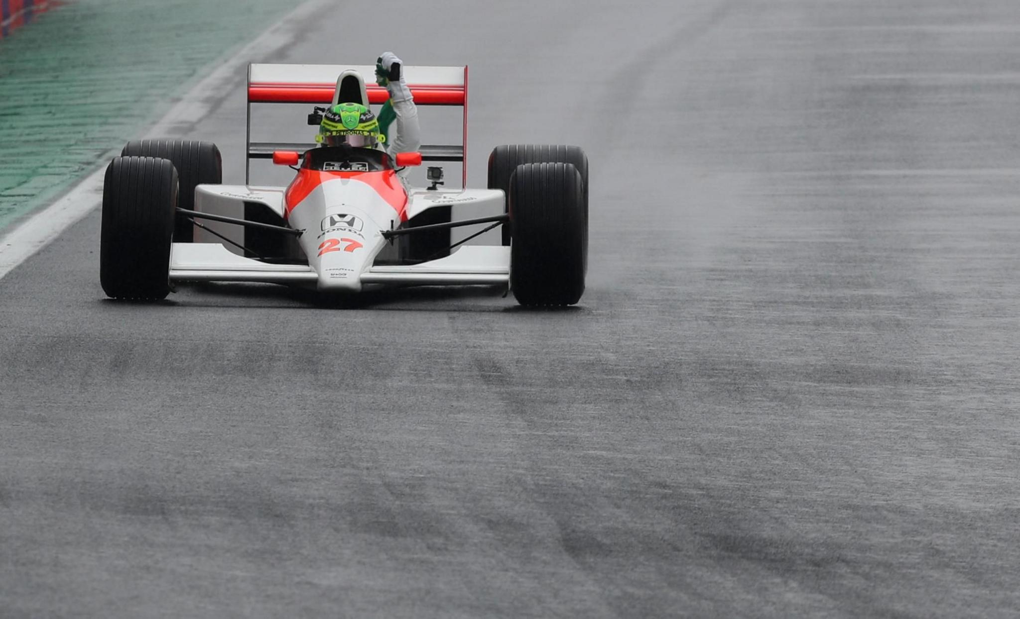 Mercedes' Lewis Hamilton waves the Brazilian flag as he drives the McLaren MP4/5B of former world champion driver Ayrton Senna 