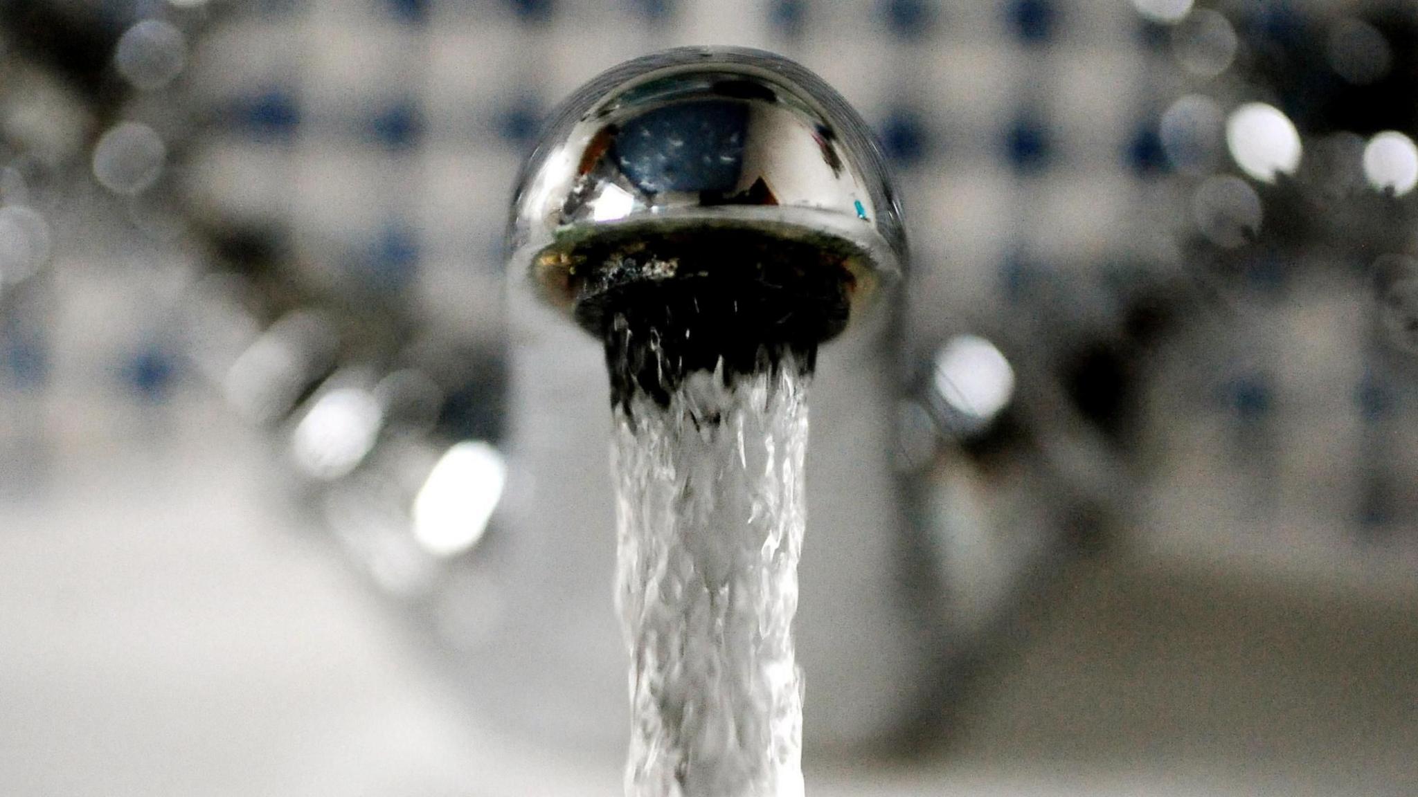 Water flows out of a metal tap