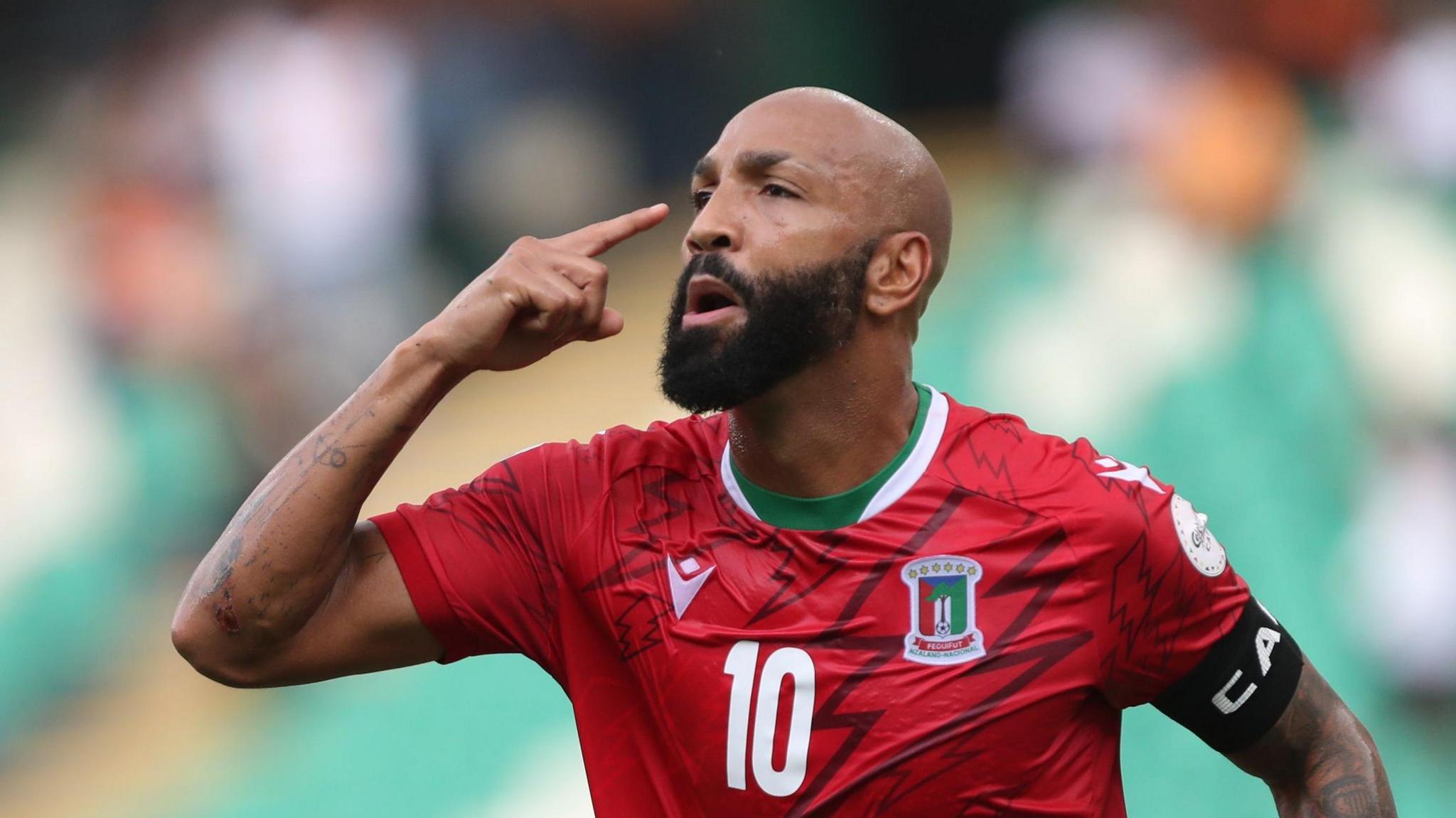 Emilio Nsue points to his head with his right hand as he celebrates a goal for Equatorial Guinea